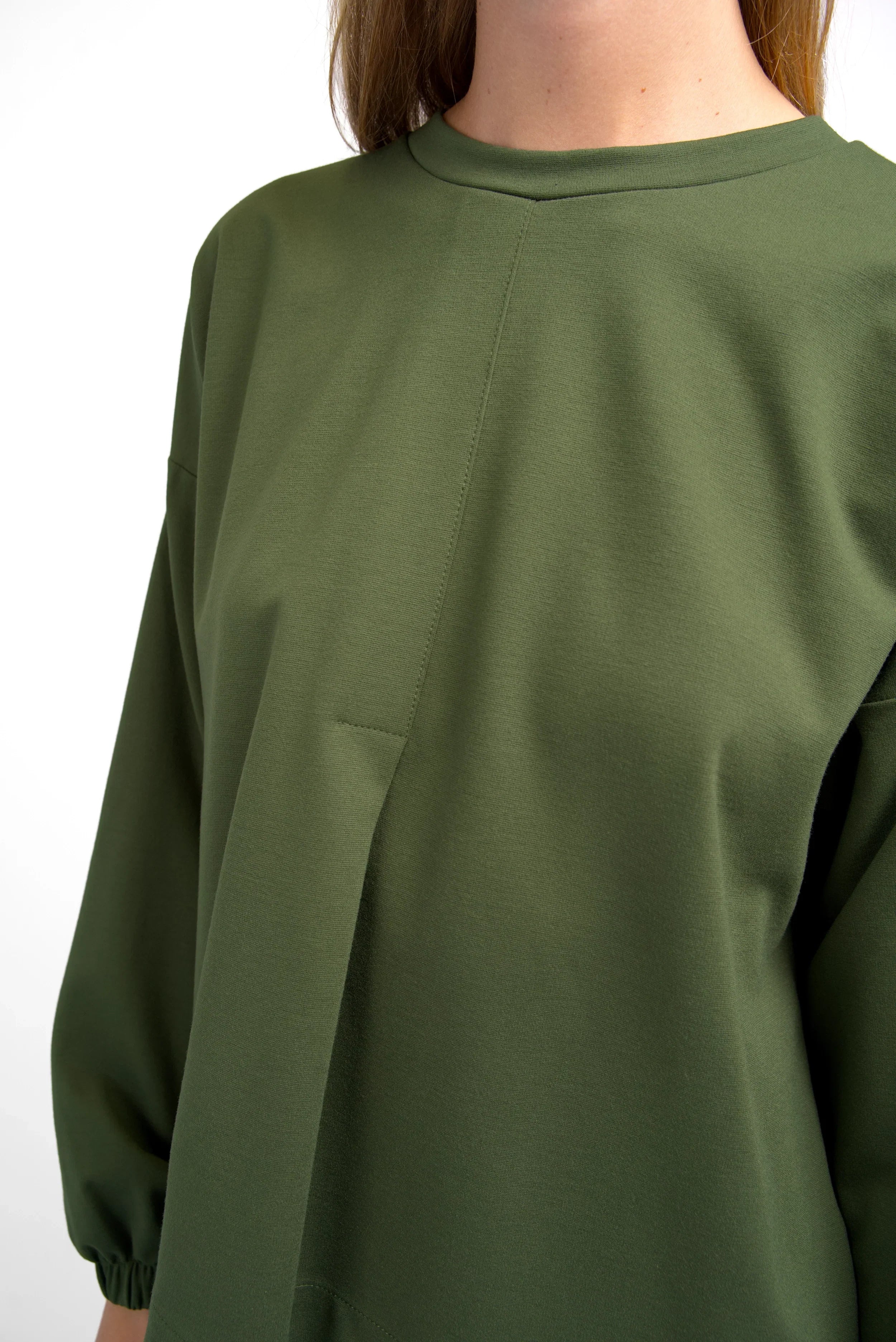 HAGLA Shirt in olive green with round neckline, elastic cuffs, front stitched pleat, relaxed fit, and longer back hem