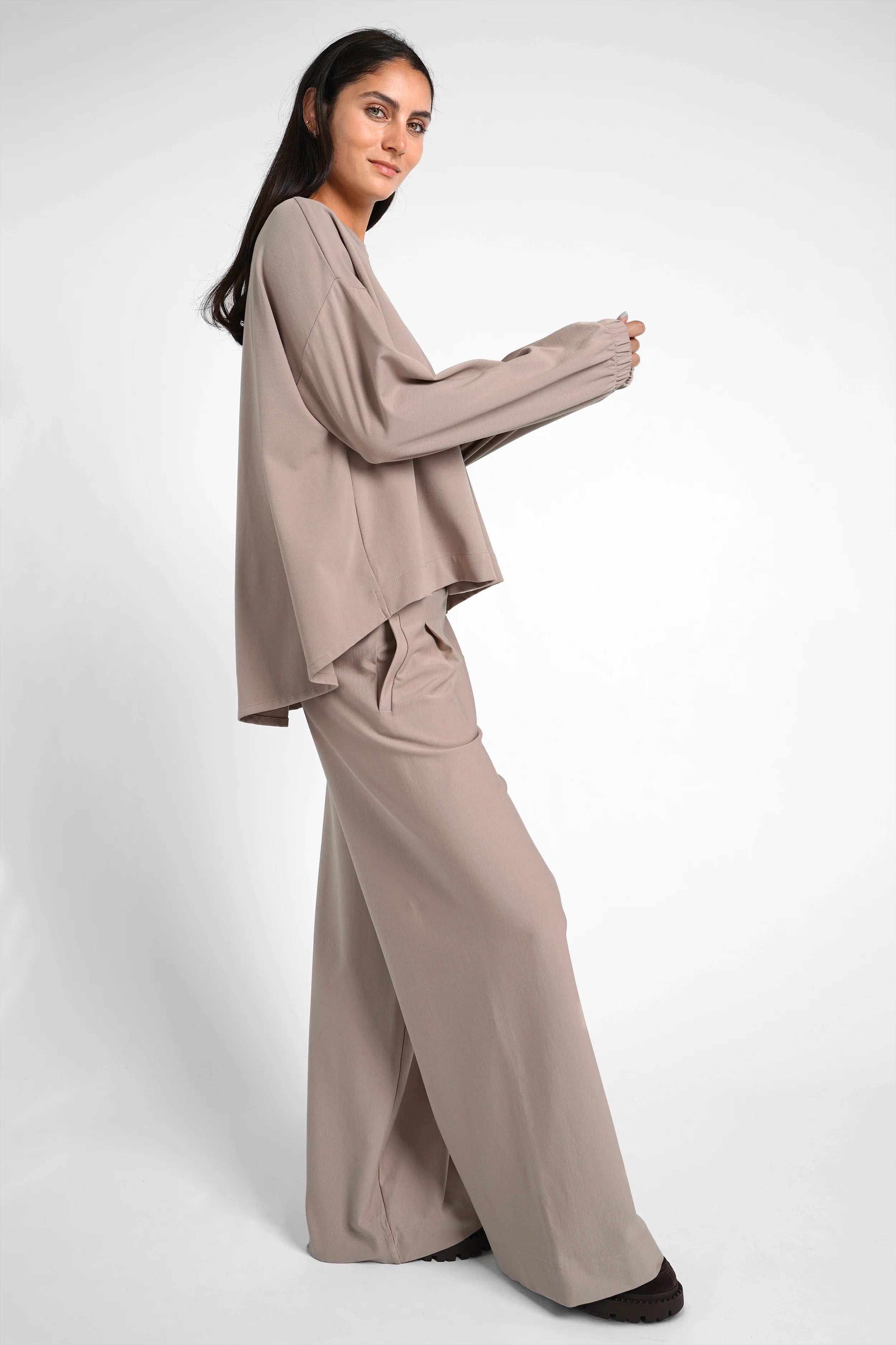 Woman wearing a beige HAGLA Shirt with elastic cuffs and relaxed fit paired with matching wide-leg pants against a white background