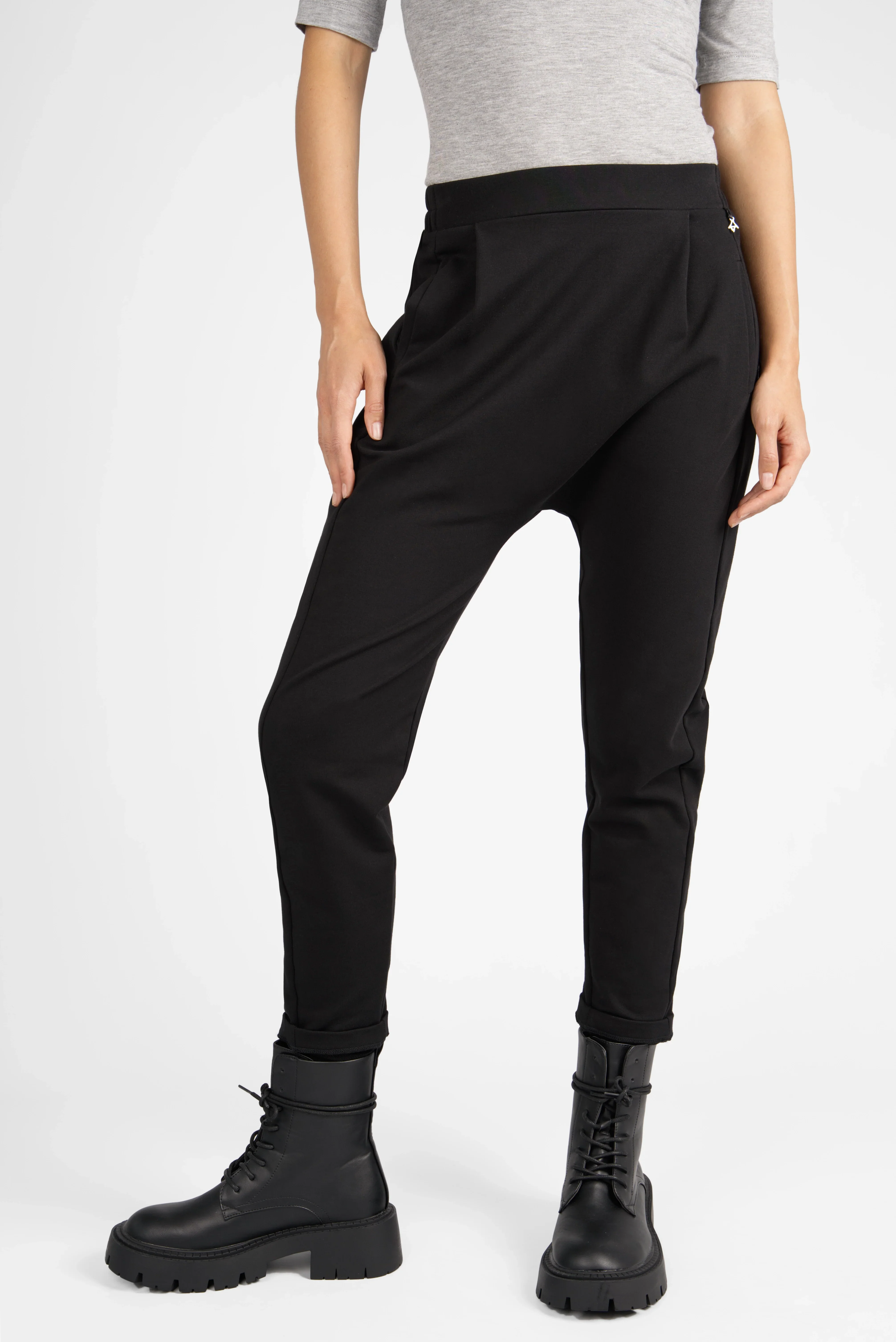 Schwarze HANNA.K Tapered Sweathose mit elastischem Bund und schmal zulaufendem Bein, getragen von Model mit grauem Oberteil und schwarzen Boots.