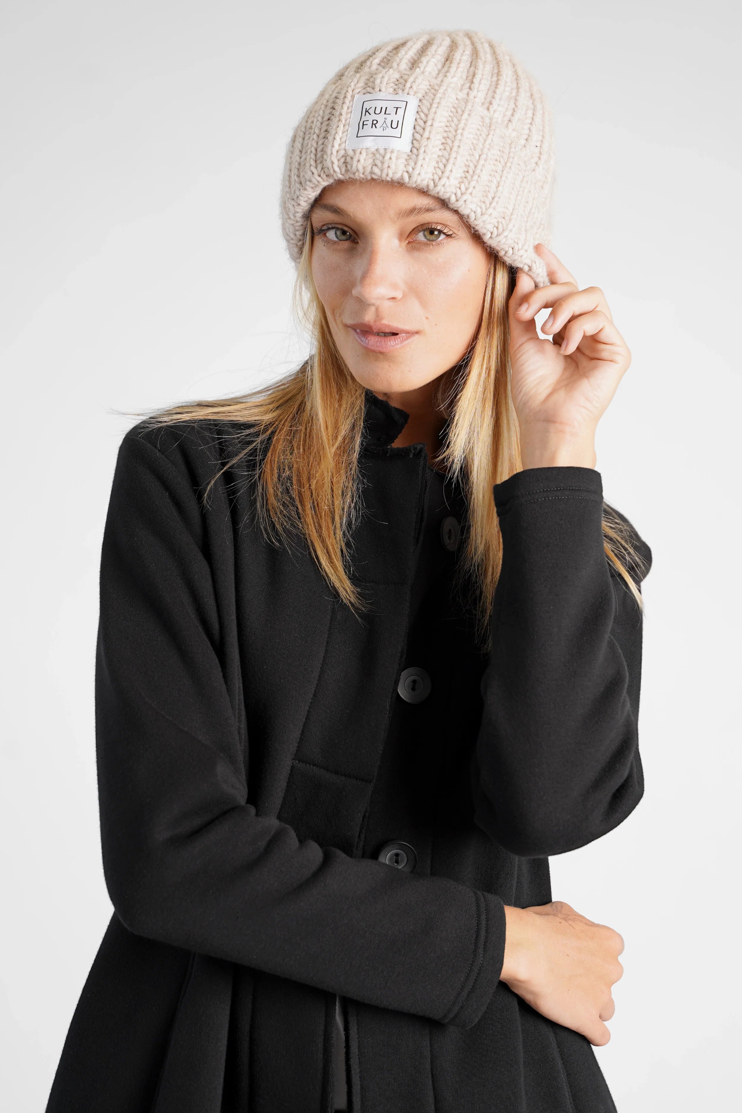 Frau trägt HATY Strickmütze aus grobem Rippstrick mit breitem Umschlag und Kultfrau-Logo vorne