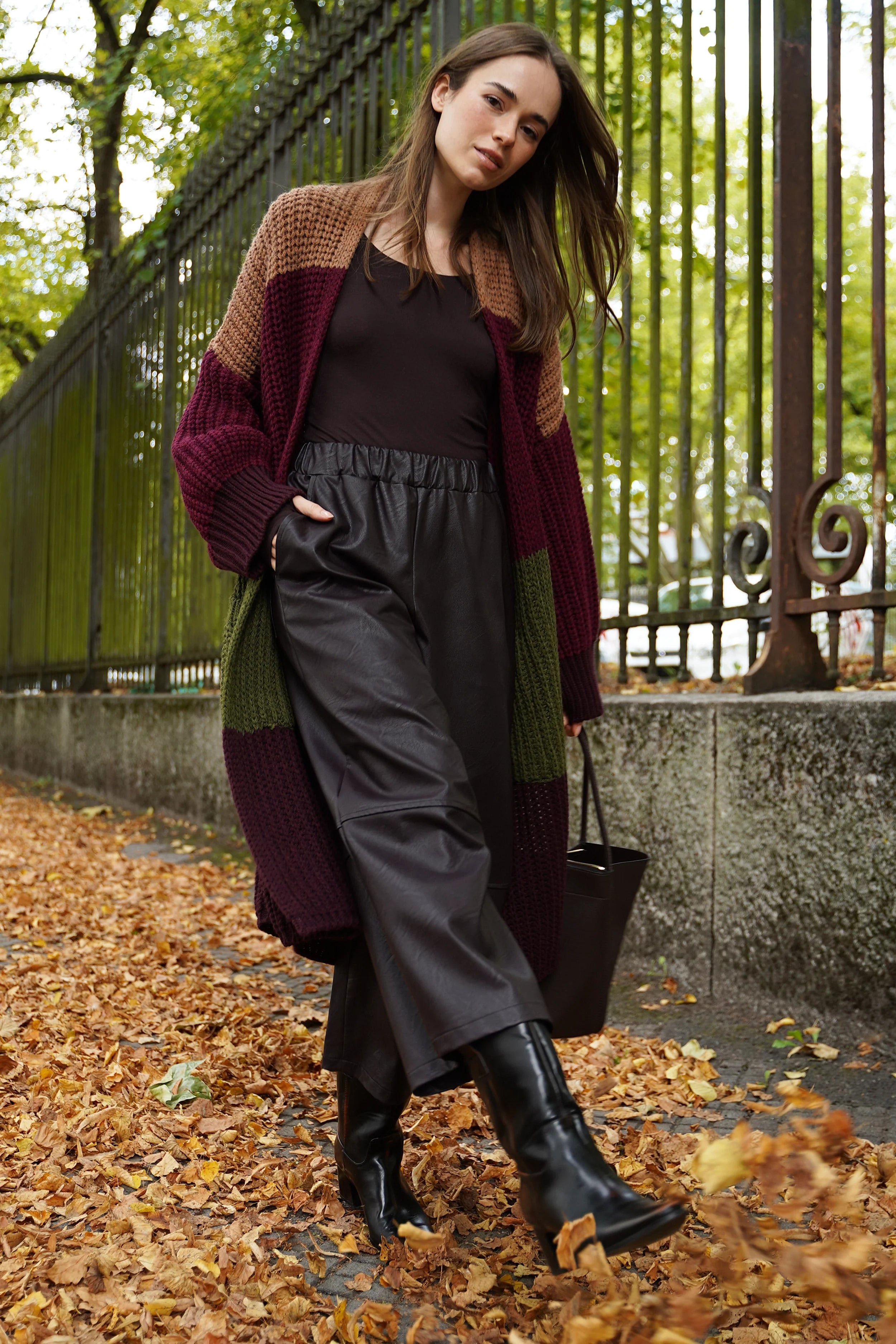 Frau trägt HERA Wide Leg Hose aus schwarzem Eco-Leder mit elastischem Bund und weiten Beinen im herbstlichen Park