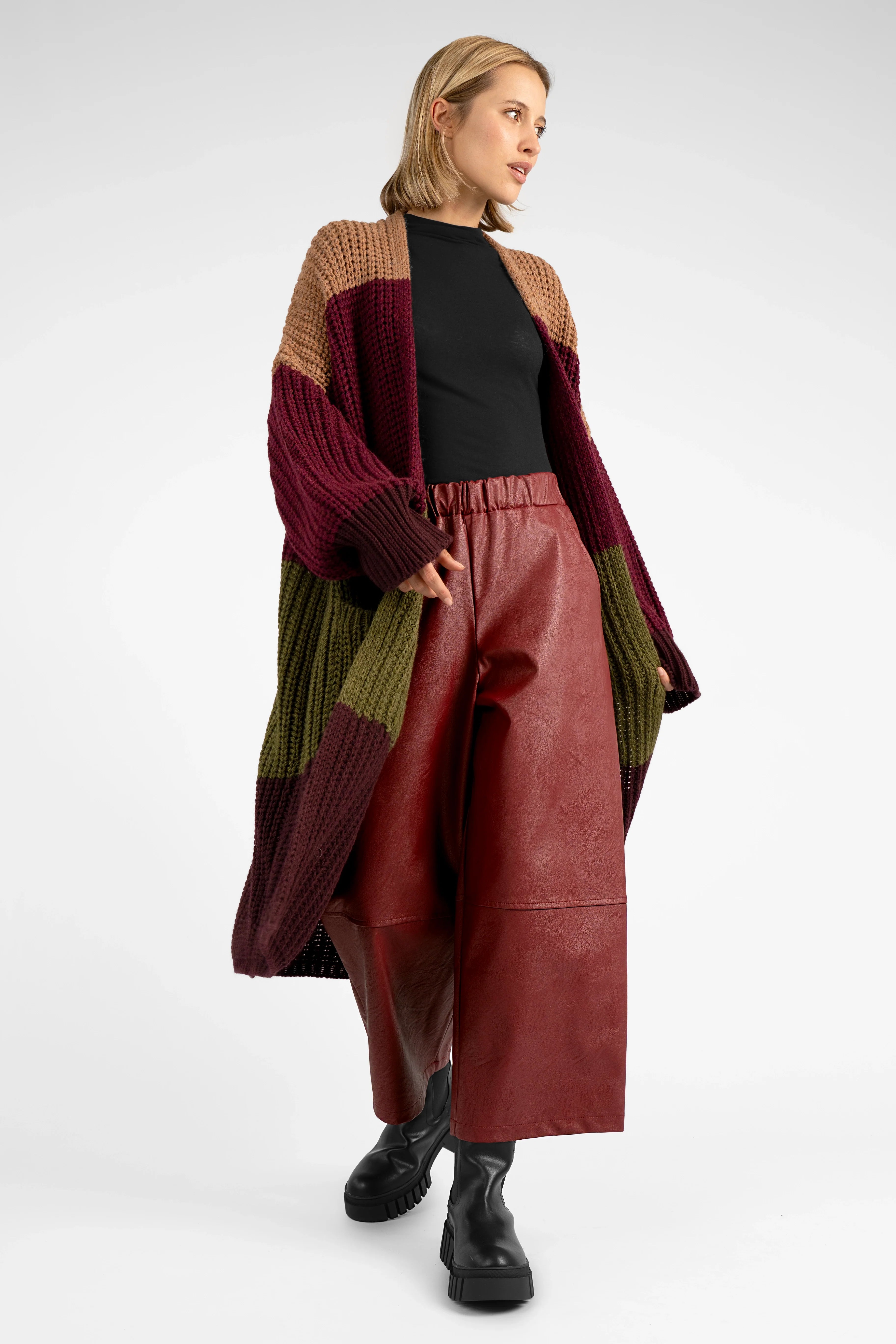 Woman wearing HERA Wide Leg Hose in soft eco-leather with elastic waistband and relaxed fit, paired with color-block cardigan and black boots