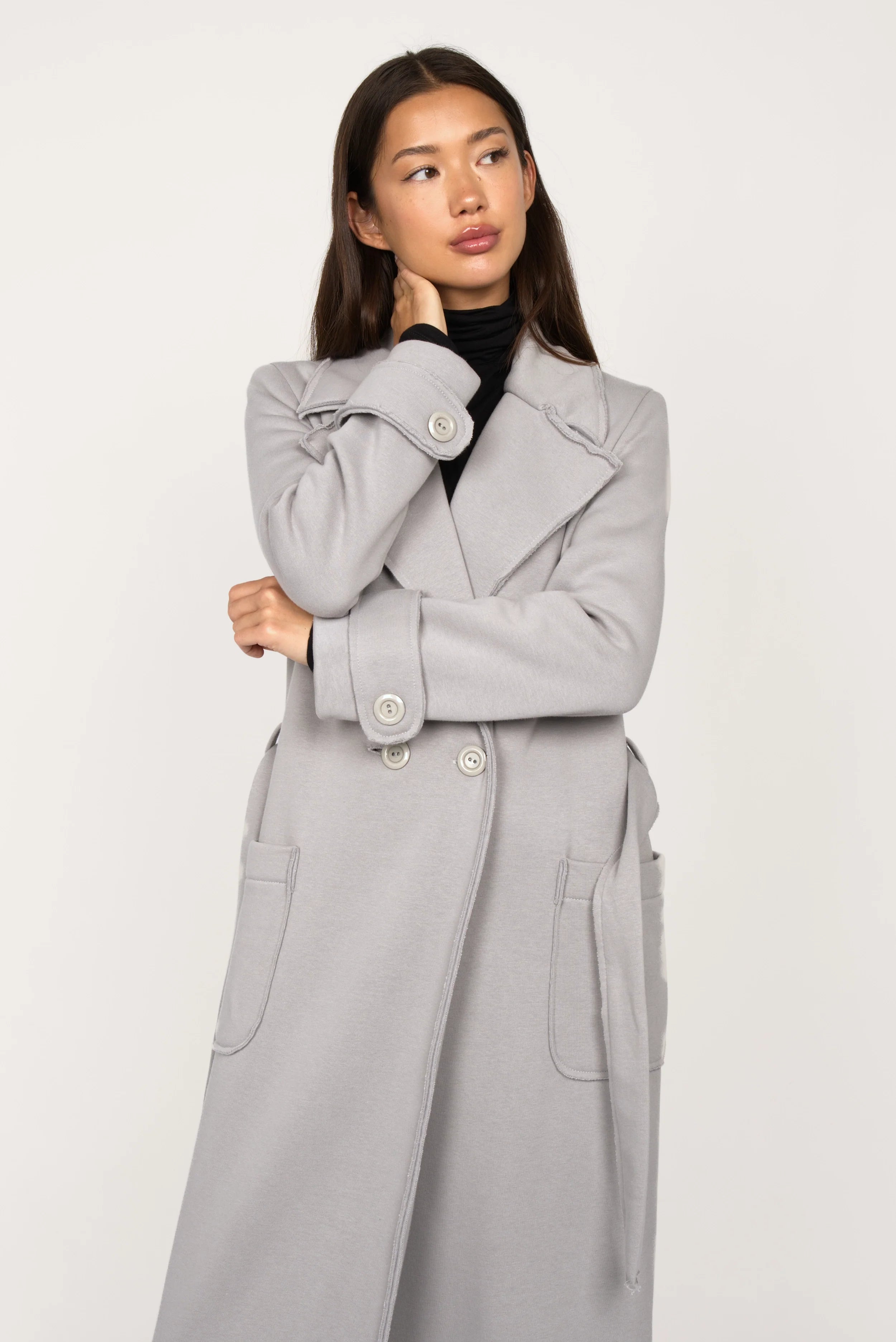 Frau trägt hellgrauen INGE Sweatmantel mit Reverskragen, Schulterpolstern und Bindegürtel