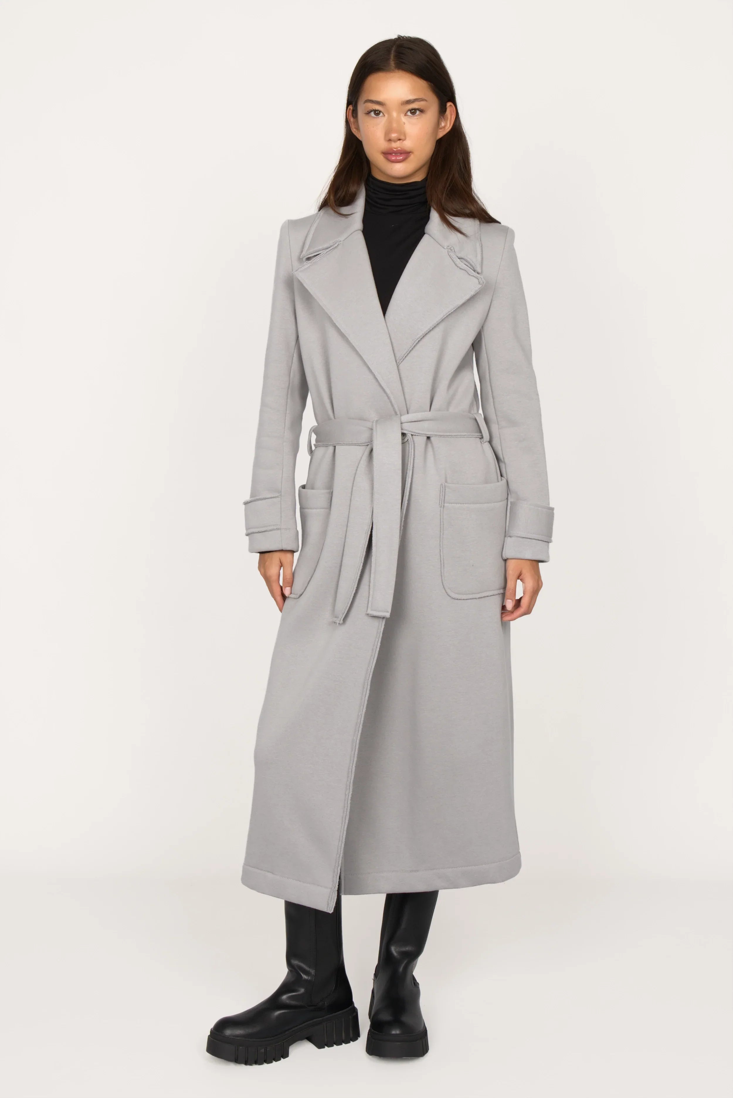 Frau trägt grauen INGE Sweatmantel mit Reverskragen, großen Taschen und Bindegürtel