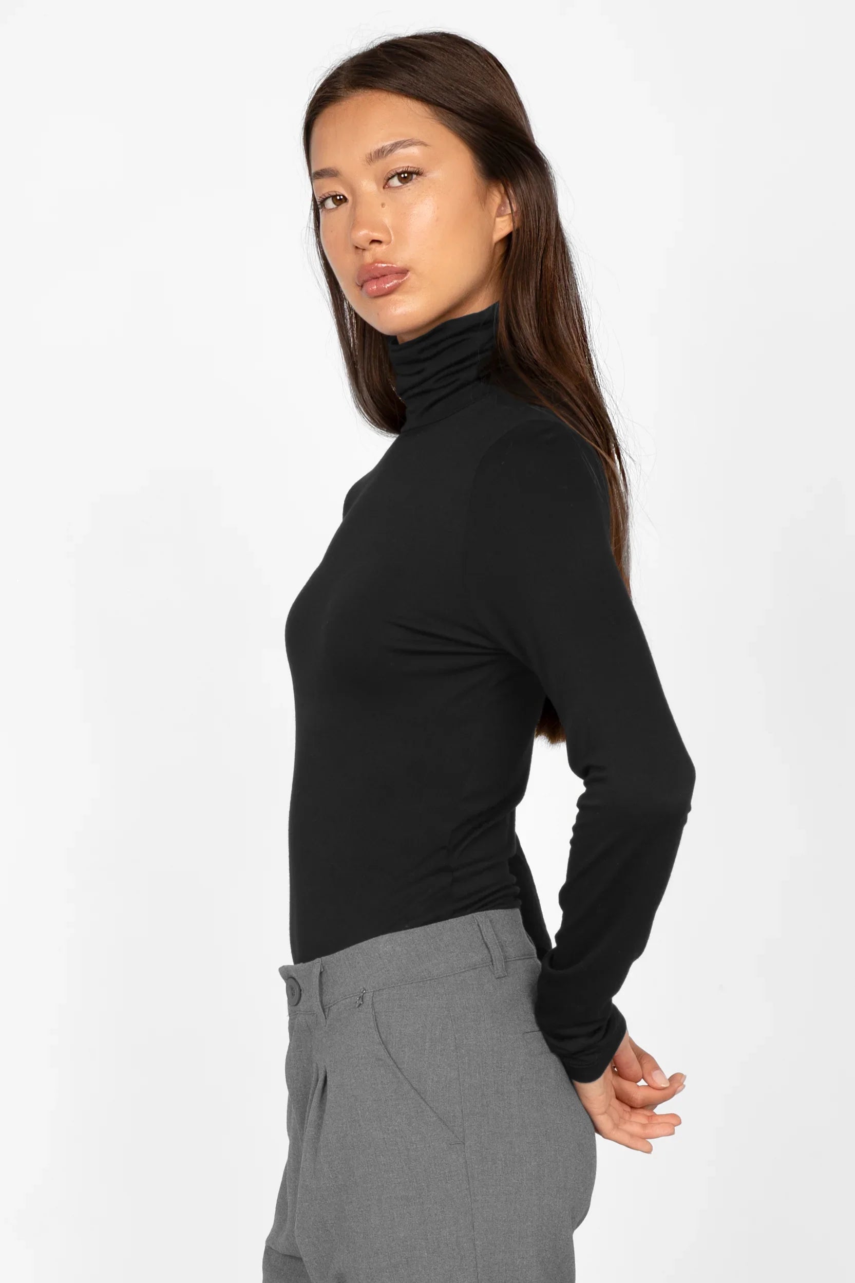 Frau trägt schwarzes, slim-fit Longsleeve mit Rollkragen und extra langen Ärmeln aus weichem Jersey