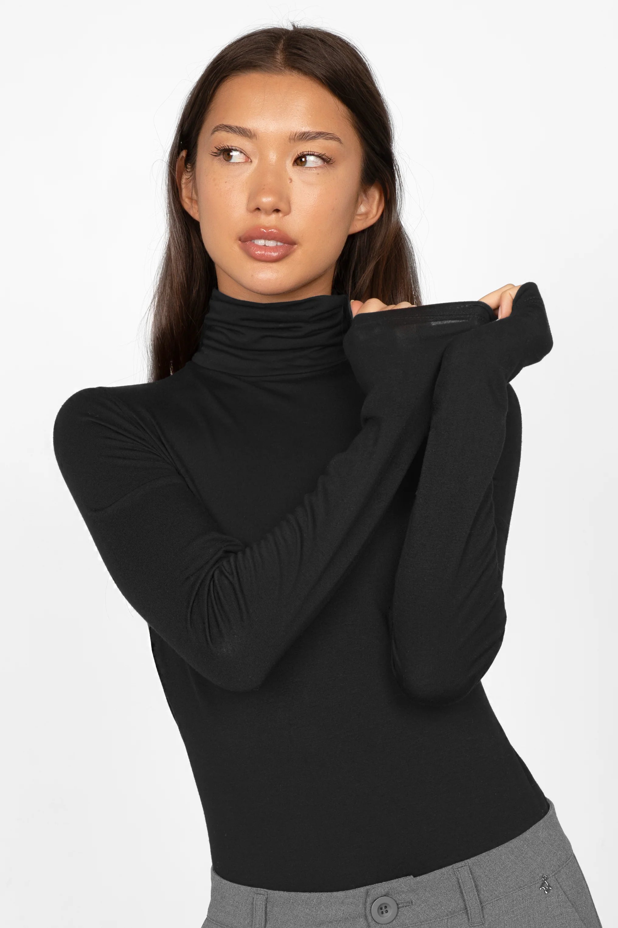 Frau trägt schwarzes INNEKA Longsleeve mit Rollkragen und extra langen Ärmeln in Slim Fit