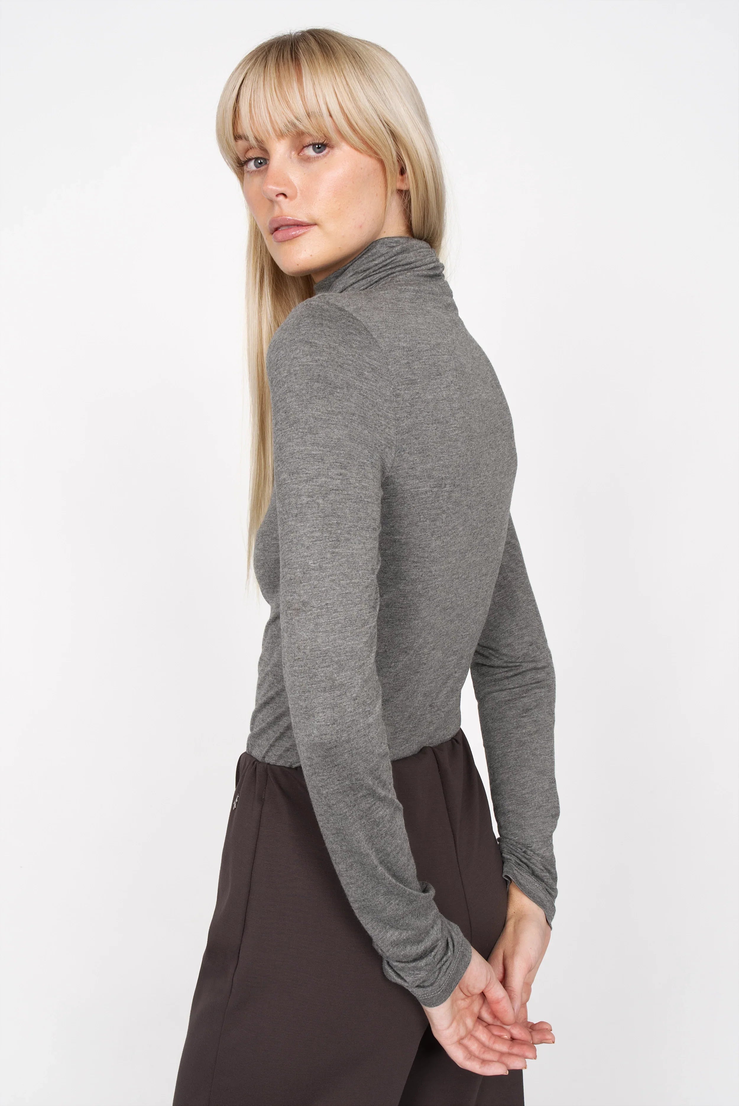 Frau trägt graues INNEKA Longsleeve mit Rollkragen und extra langen Ärmeln aus weichem Jersey