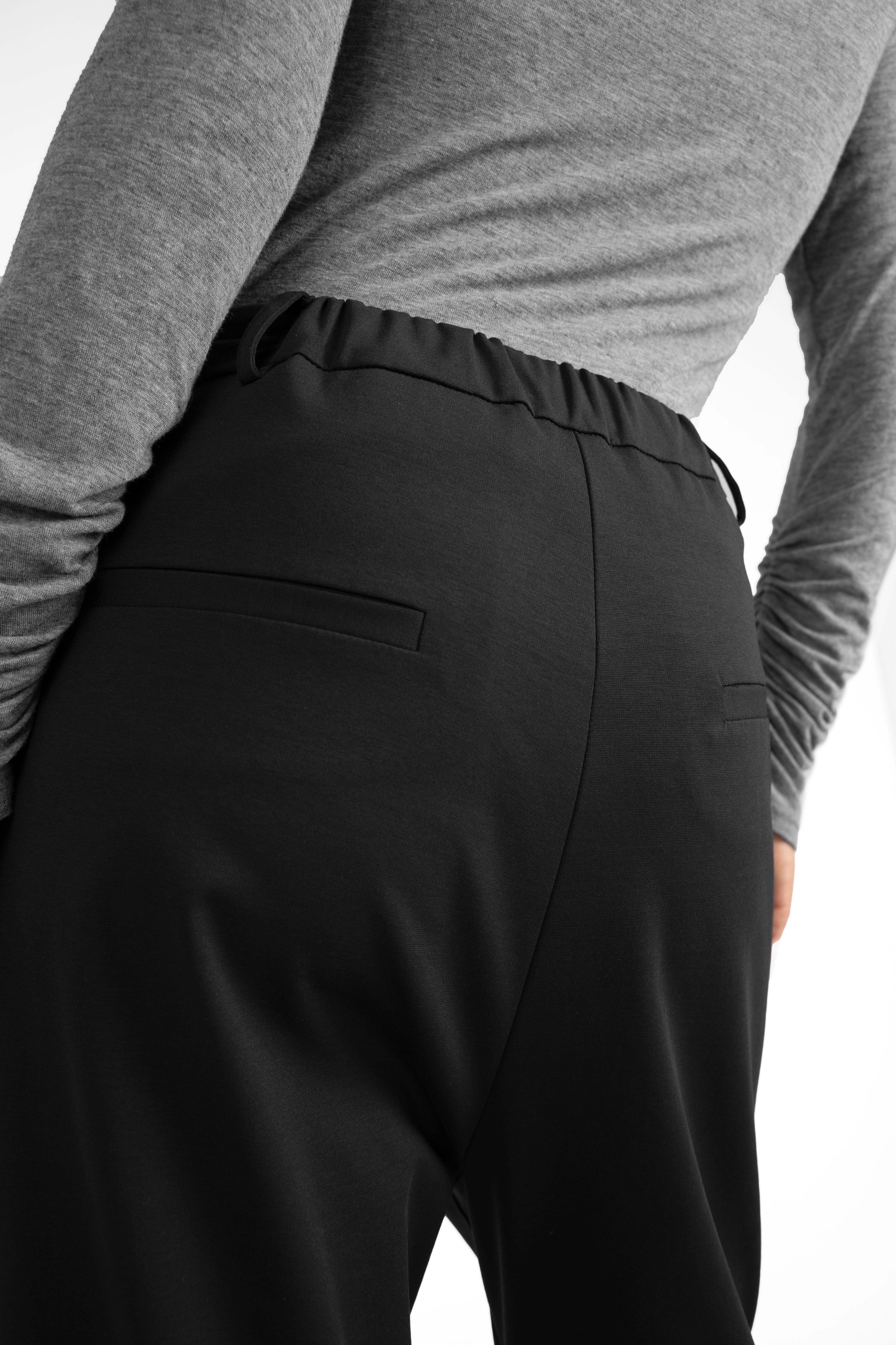 Back view of JALDI Cropped Tapered Hose in black with elastic waistband and tapered legs.