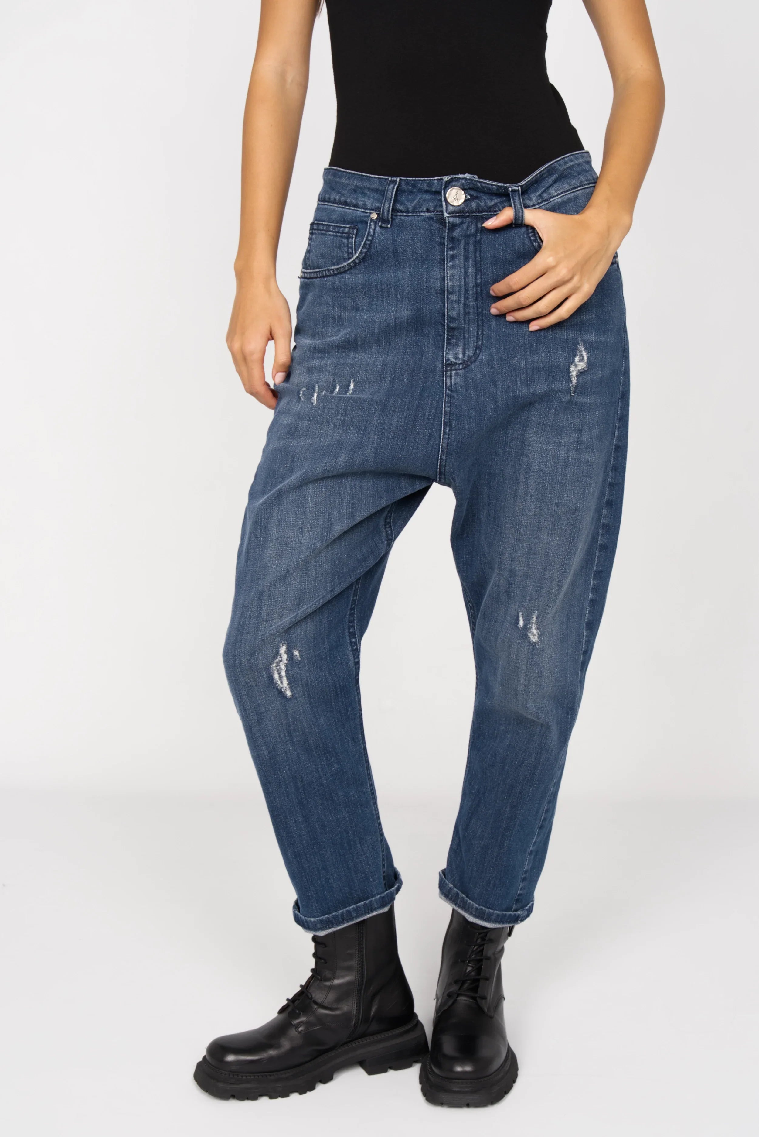 Medium blue baggy jeans with relaxed fit, subtle distressed details, and 5 pockets worn with black boots.