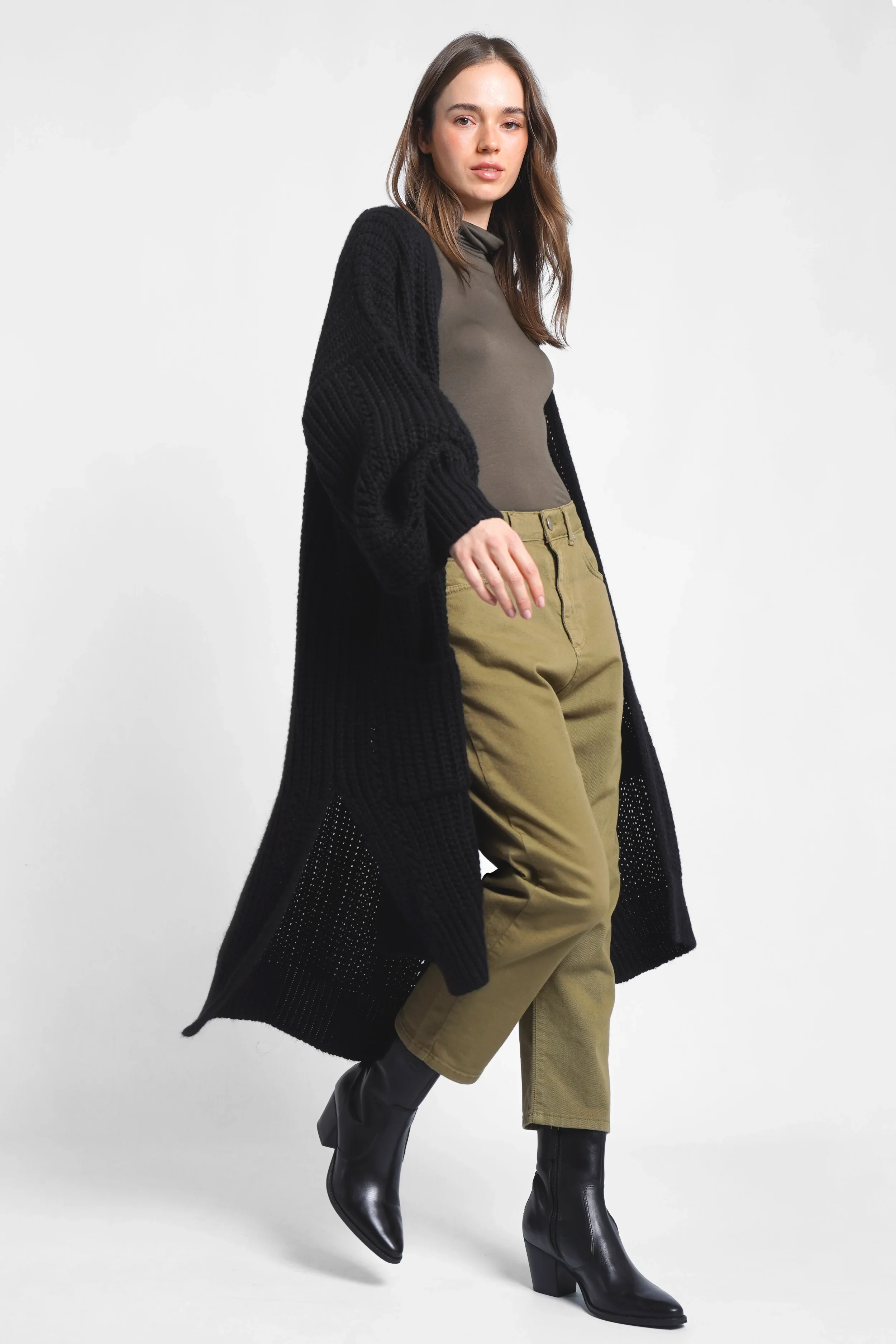 Woman wearing relaxed fit baggy jeans with deep crotch and five pockets styled with black boots and a long black cardigan