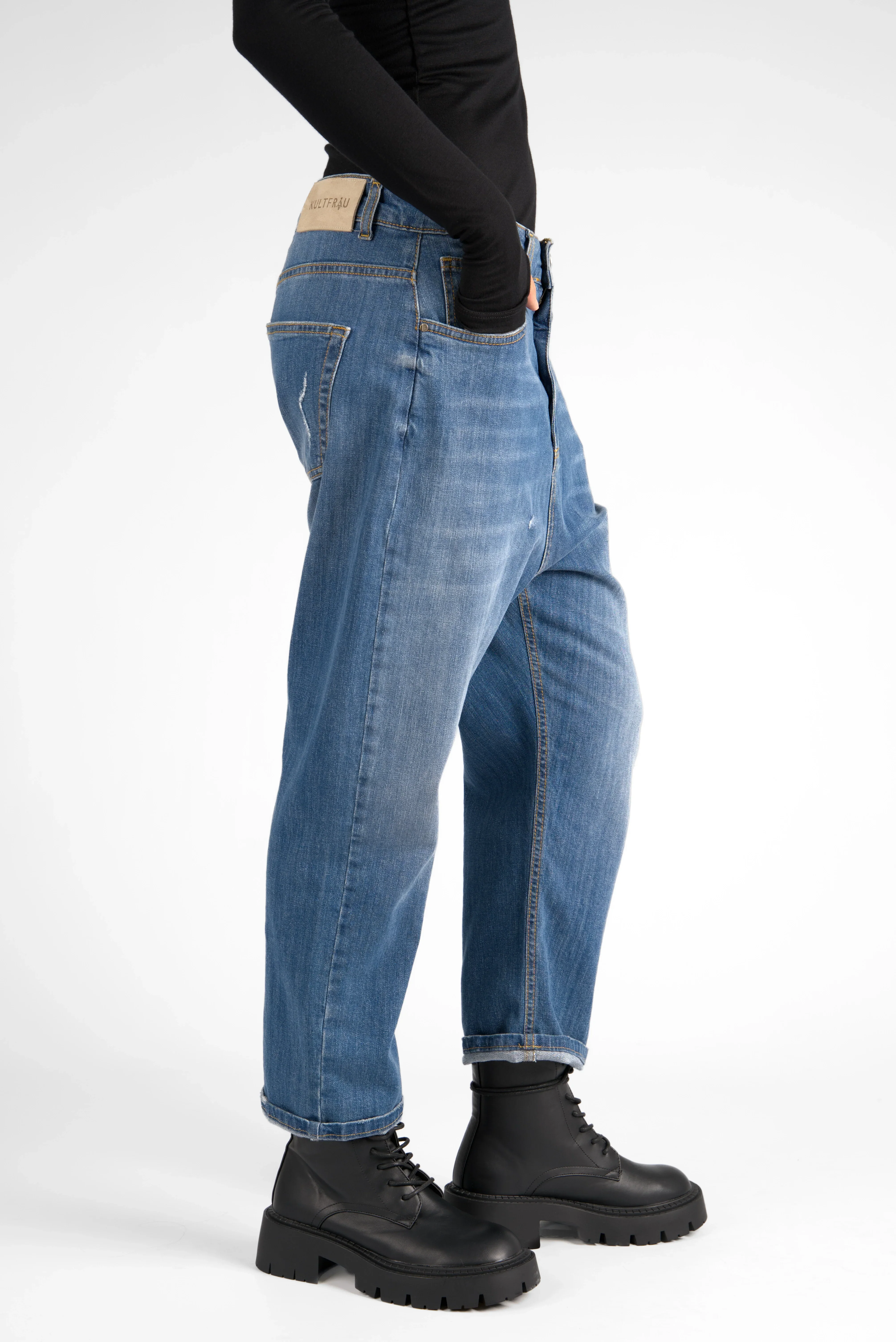 Jeany Baggy Jeans in destroyed Waschung mit ockerfarbenen Kontrastnähten und relaxed Fit, getragen mit schwarzen Boots.