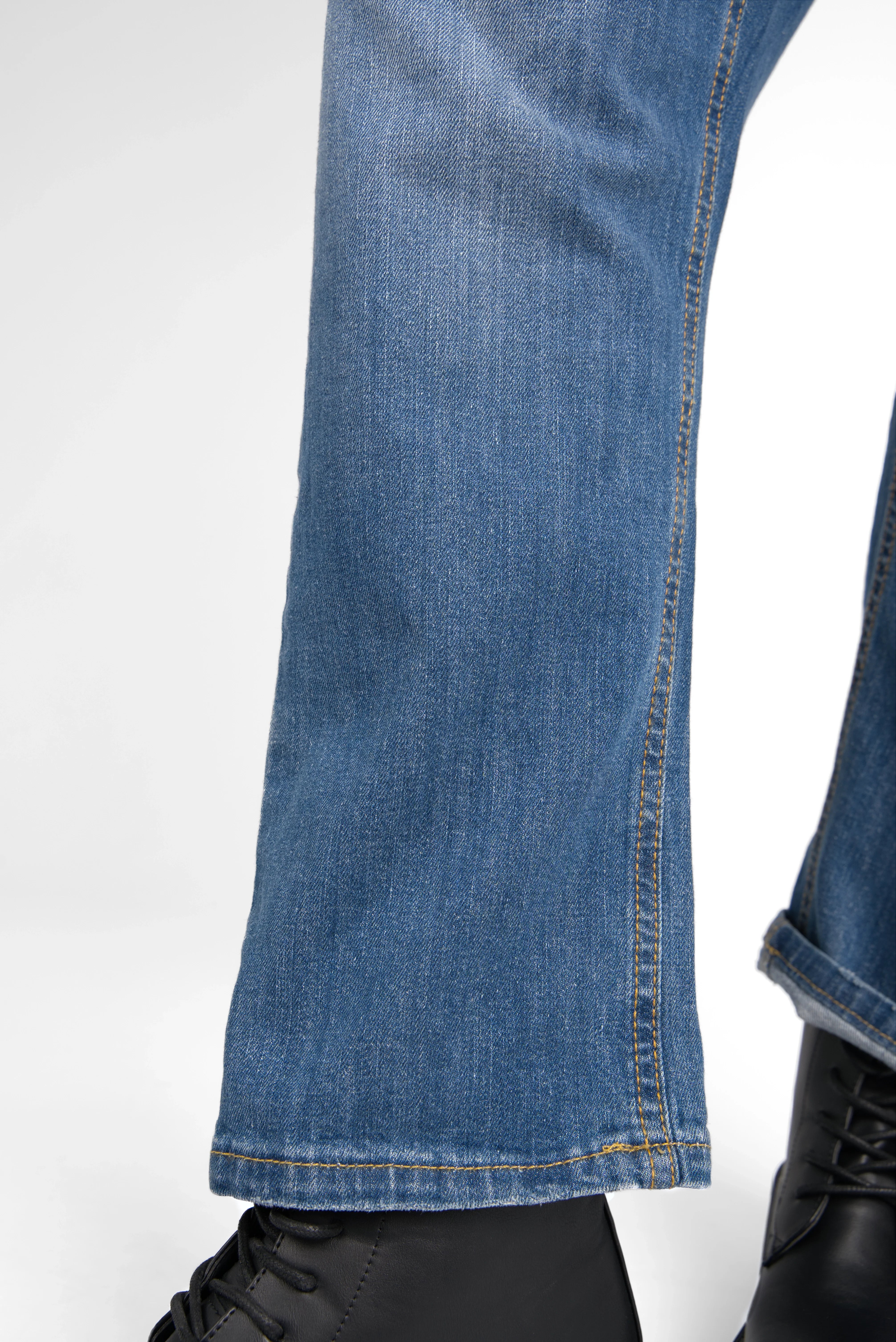 Close-up of medium blue JEANY Baggy Jeans with relaxed fit and subtle worn effects, paired with black boots