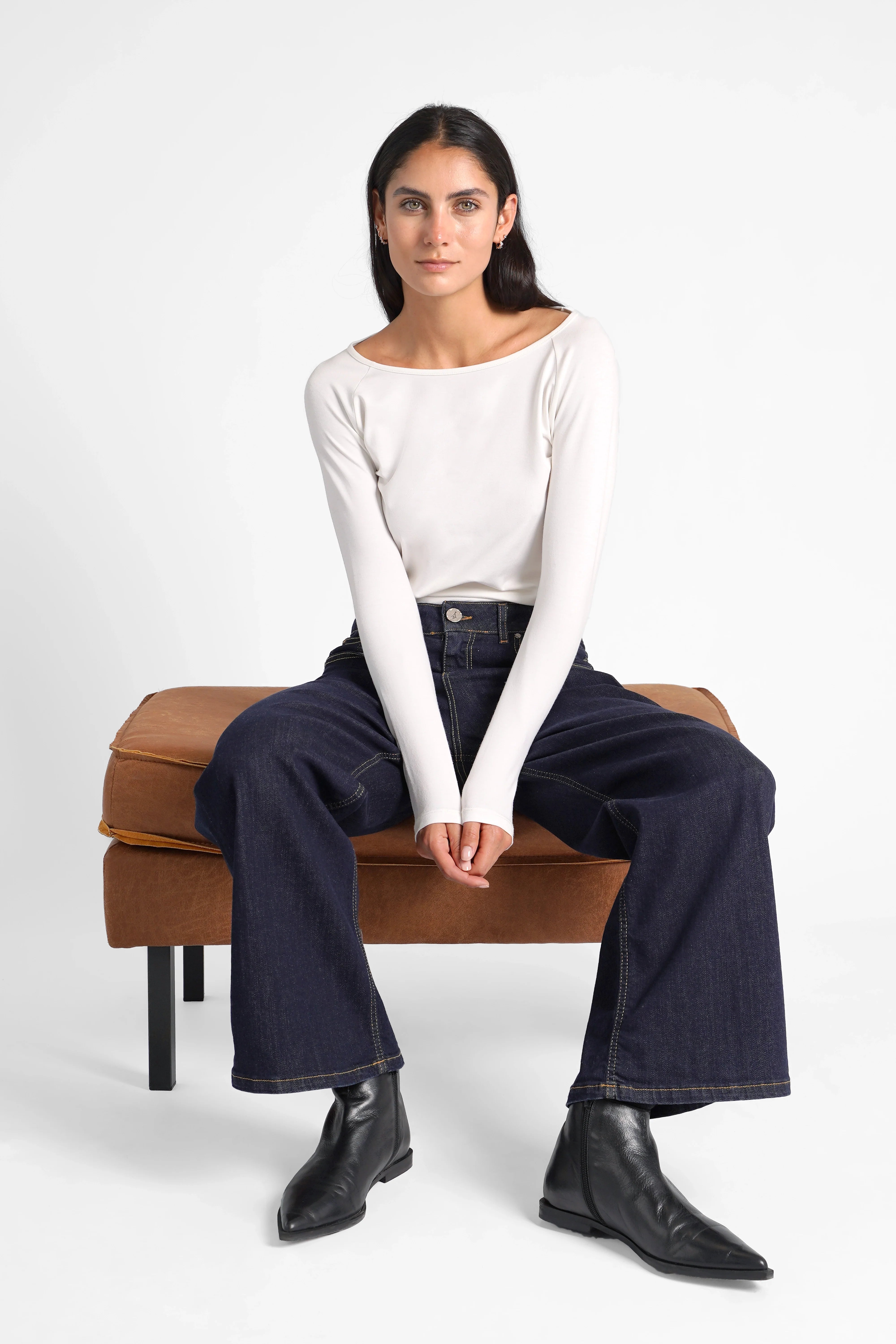 Woman sitting wearing JOOSY Wide Leg Jeans dark denim with relaxed fit and white long sleeve top