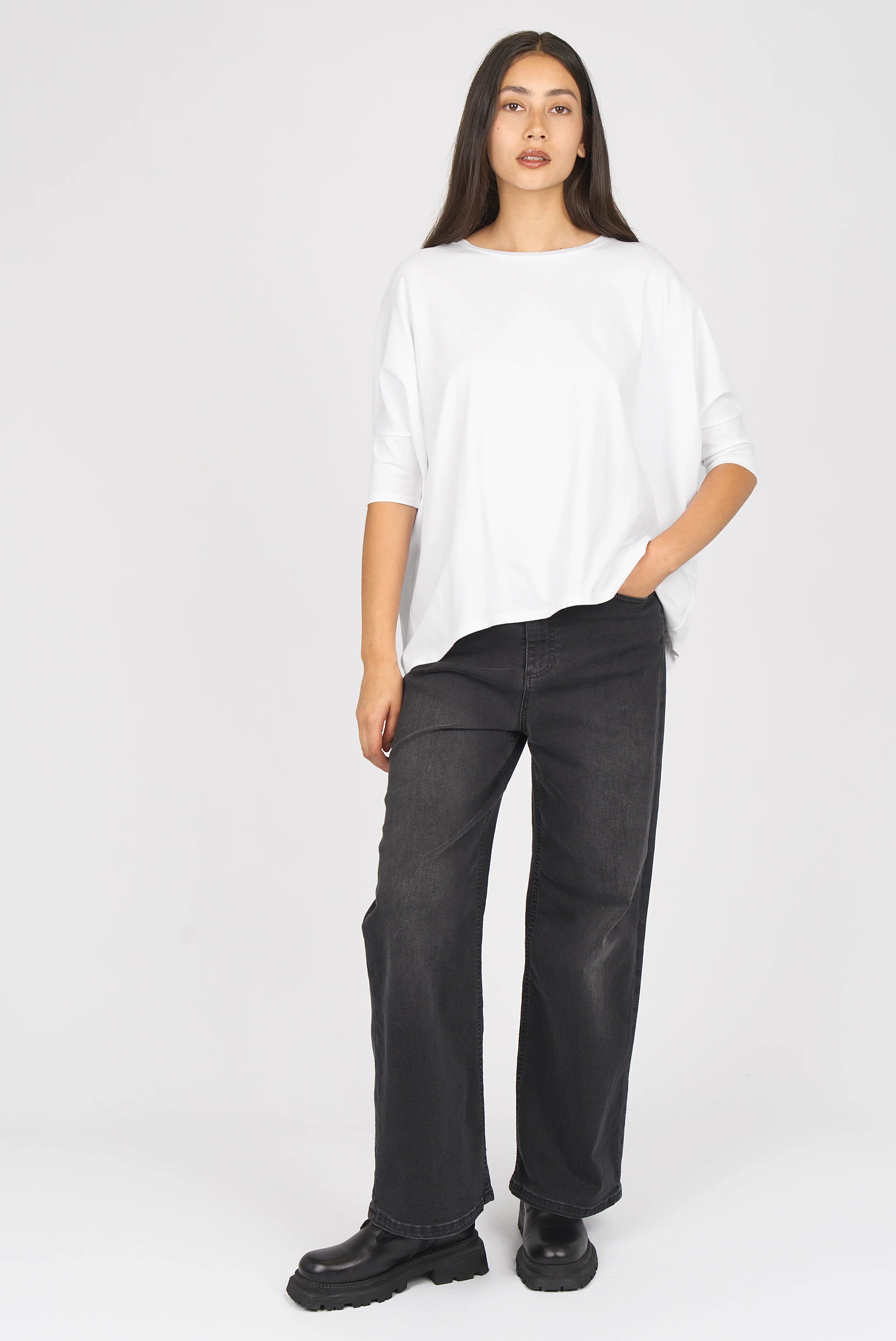 Damen trägt JOOSY Wide Leg Jeans in Faded Black mit weitem Bein und relaxed Fit kombiniert mit weißem T-Shirt und schwarzen Schuhen.