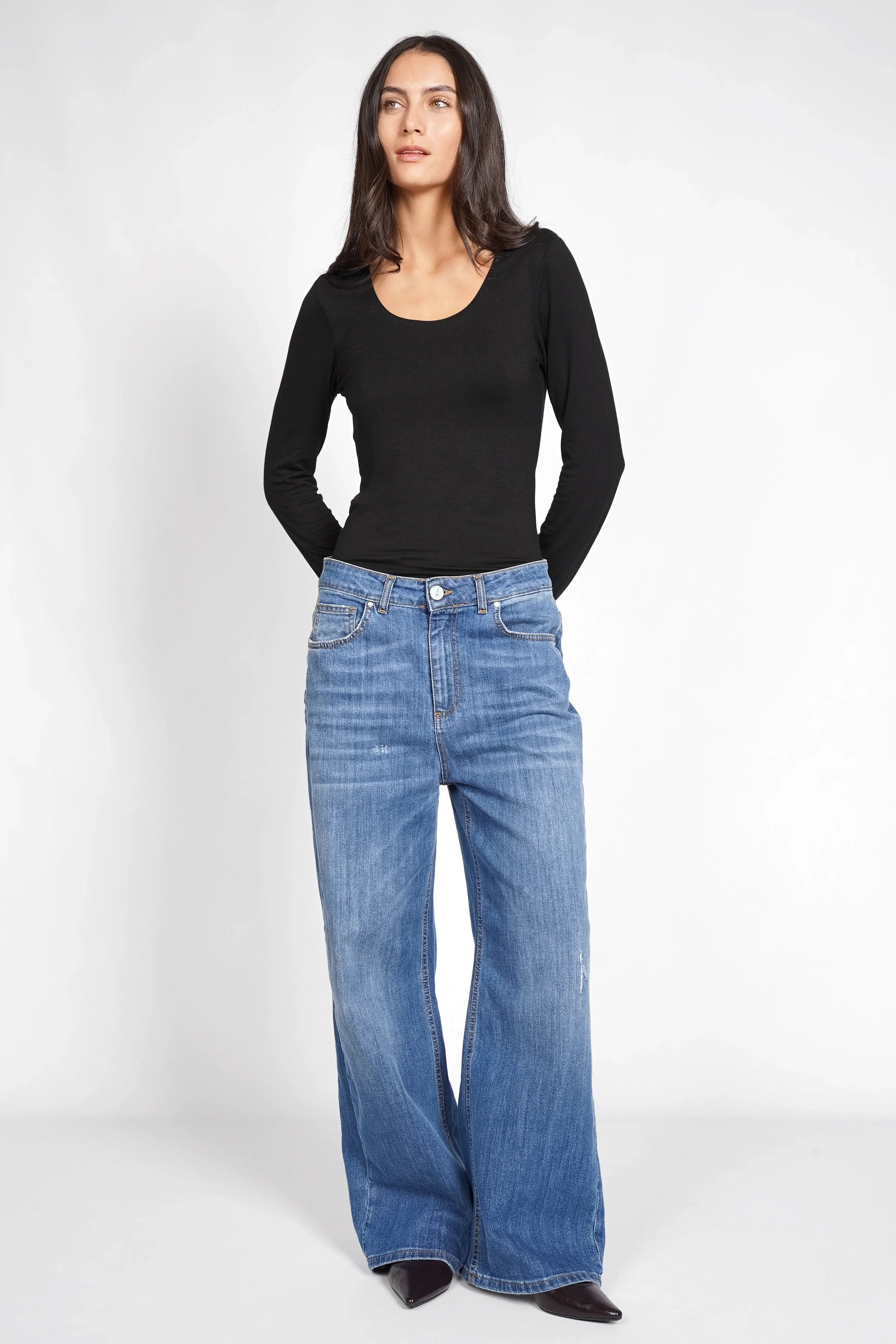 Frau trägt JOOSY Wide Leg Jeans in mittelblauer Used-Waschung mit weitem Bein und relaxed Fit