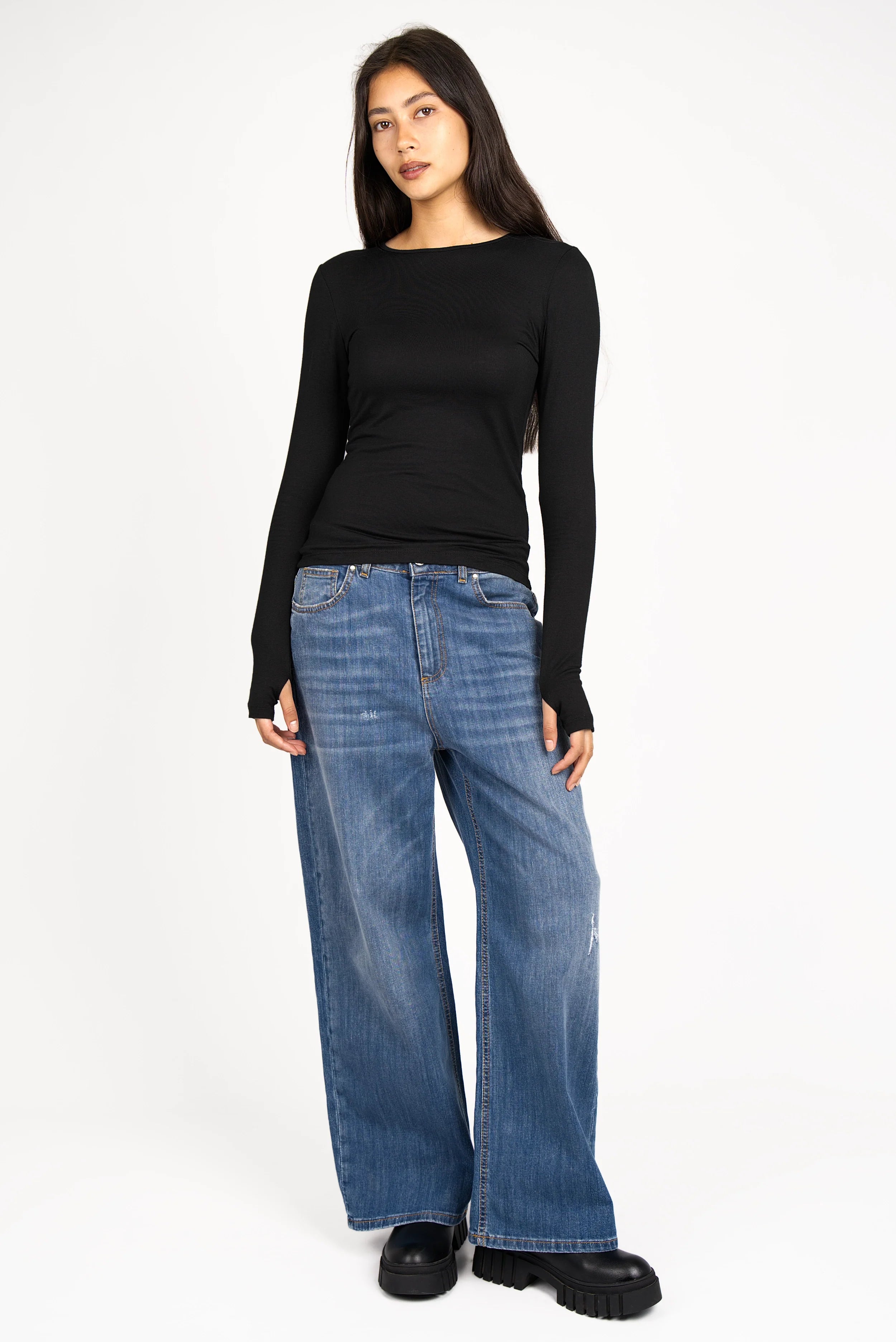 Frau trägt JOOSY Wide Leg Jeans aus italienischem, leicht elastischem Denim in mittelblauer Used-Waschung mit weitem Bein und Relaxed Fit.