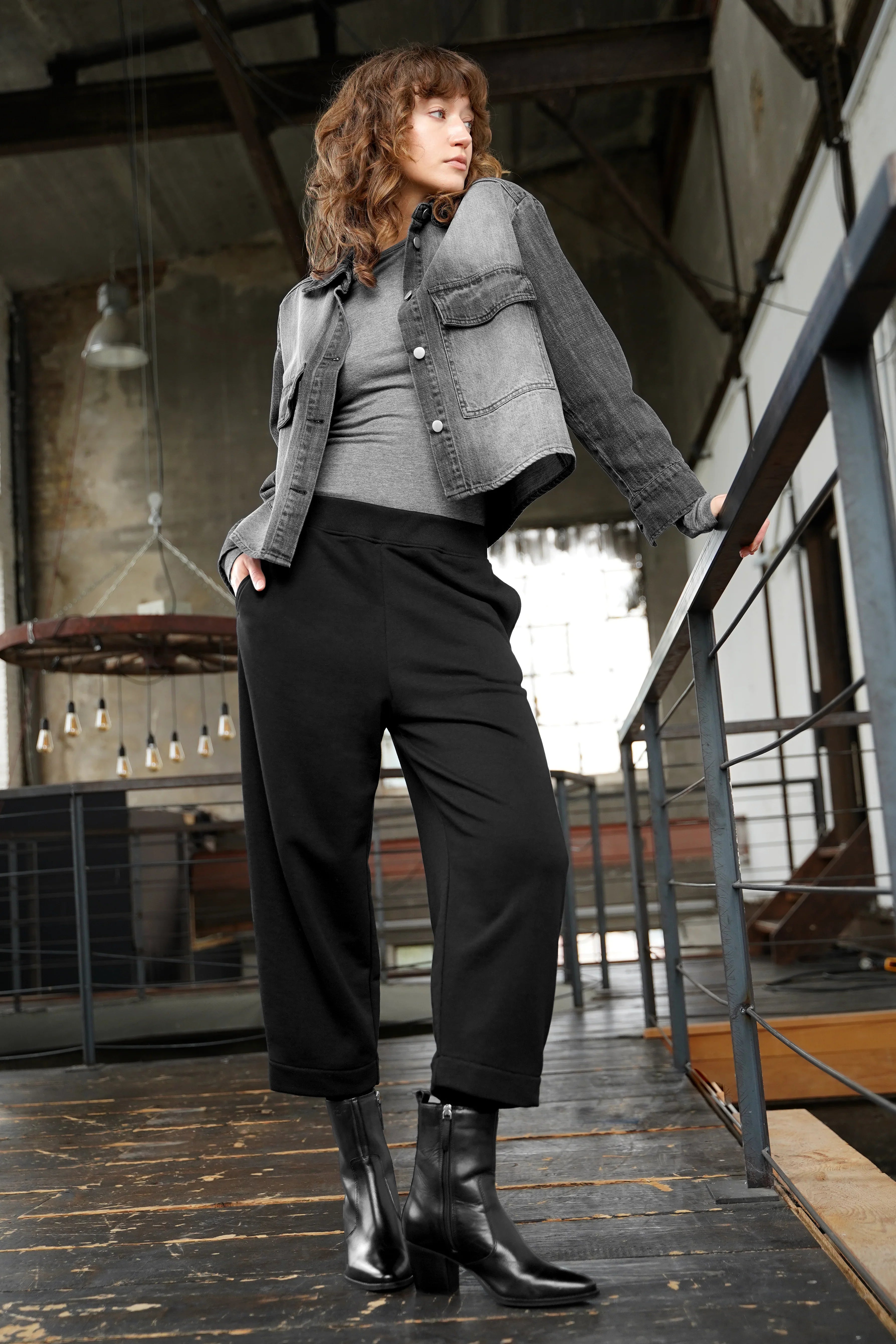 Model wearing black JOUDY Carrot Jogpant with elastic waistband and cropped carrot fit in industrial setting