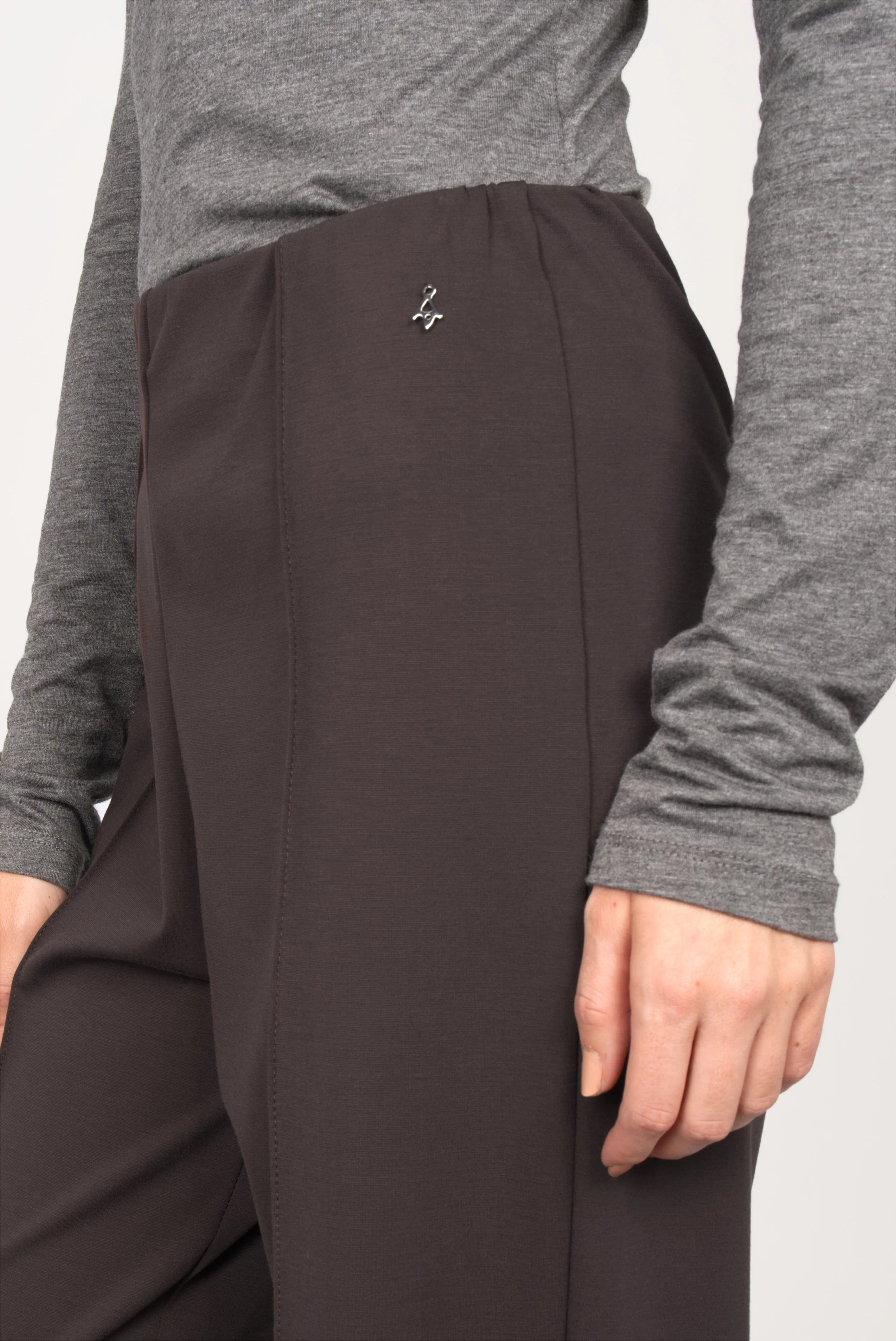 Close-up of brown KANDANEA Gerade Hose straight-leg pants with front pintucks and elastic waistband worn with a grey long-sleeve top