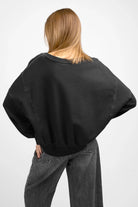 Woman wearing black KERY Cropped Sweater with oversized fit and U-boat neckline, shown from the back.