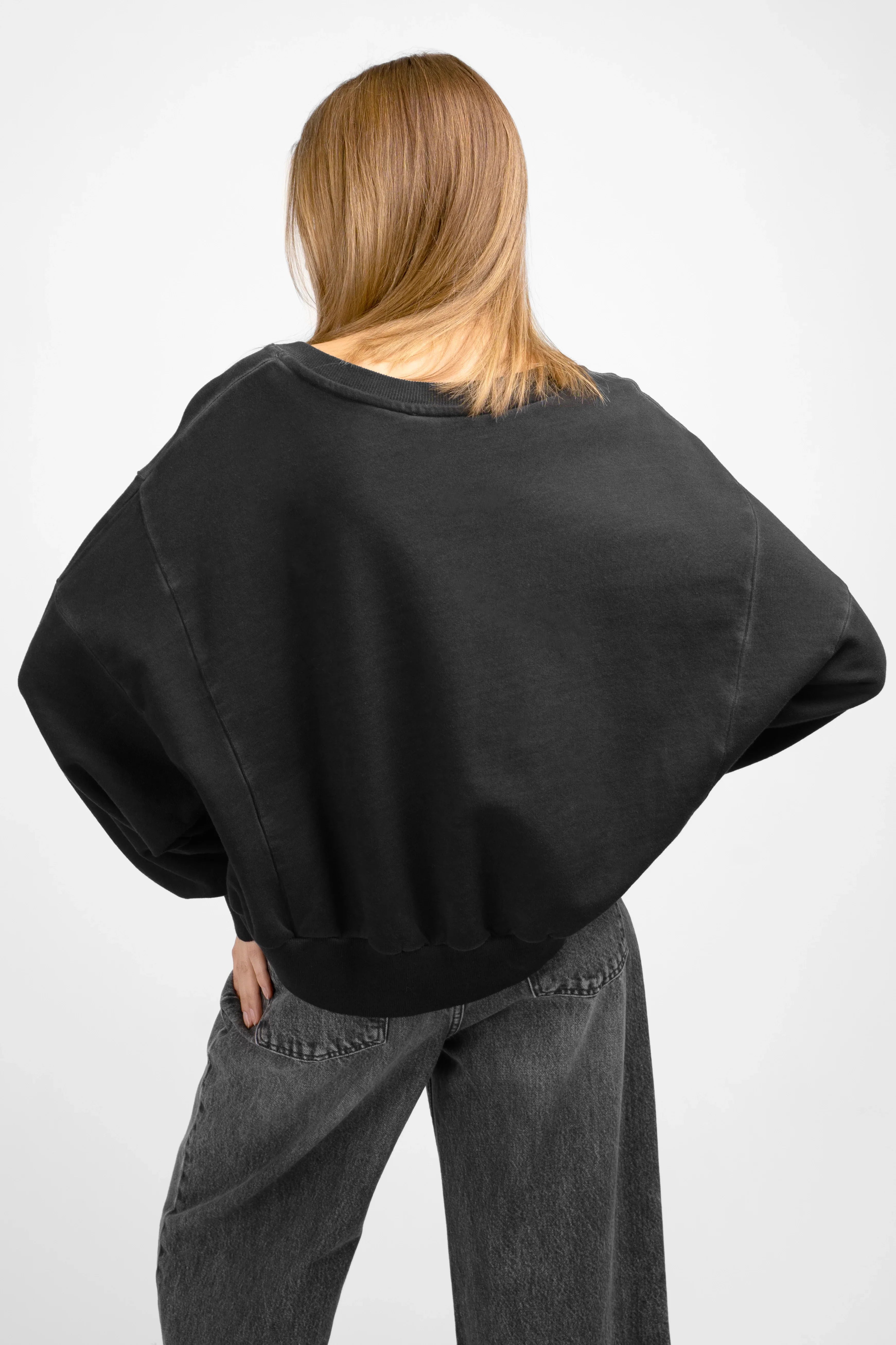 Back view of model wearing oversized black KERY Cropped Sweater with cropped length and dropped shoulders