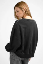 Woman wearing black KERY Cropped Sweater with oversized fit and U-boat neckline, shown from the back