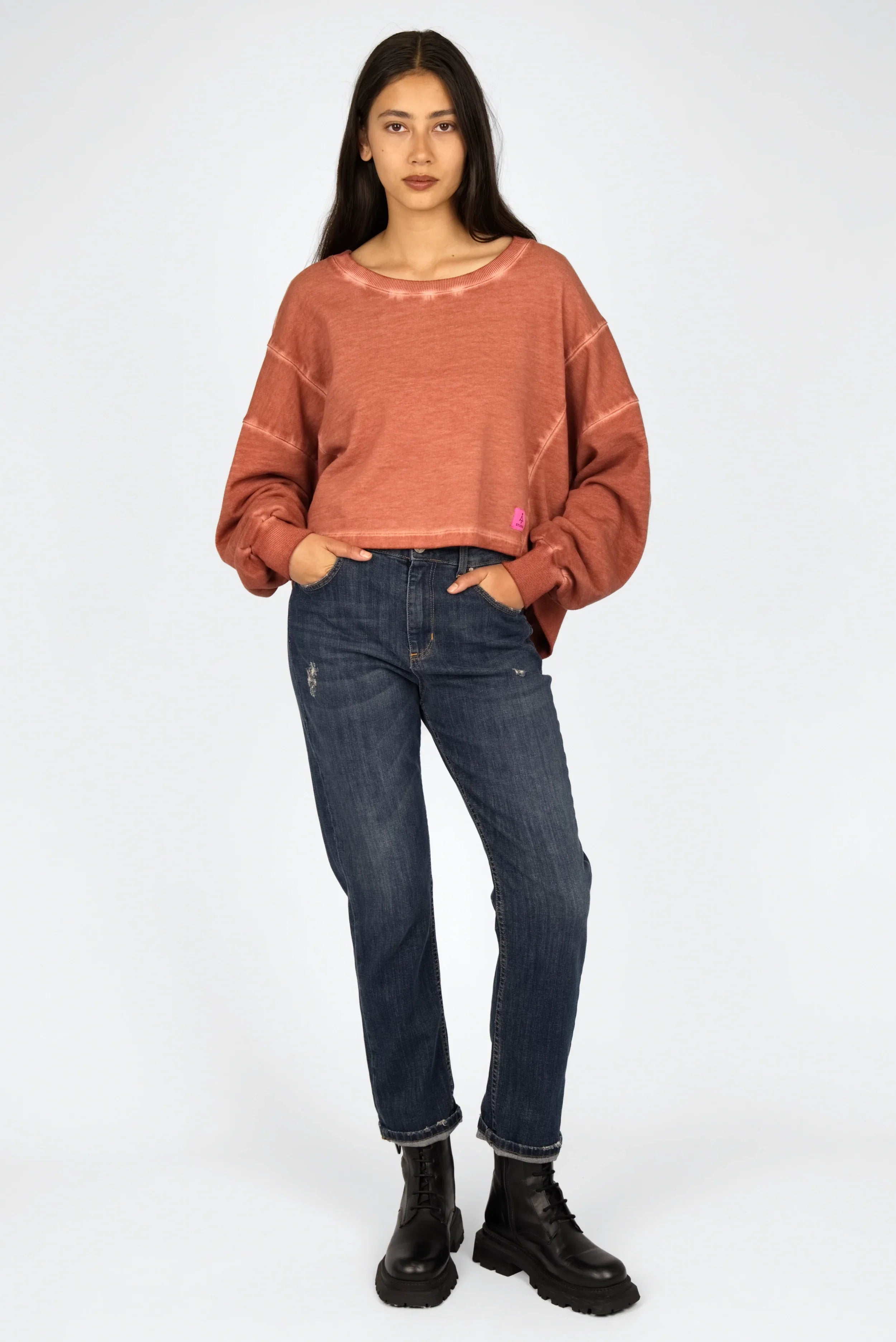 Frau trägt KERY Cropped Sweater in oversized Passform mit U-Boot Ausschnitt und cold-washed Baumwolle, kombiniert mit Jeans und schwarzen Stiefeln