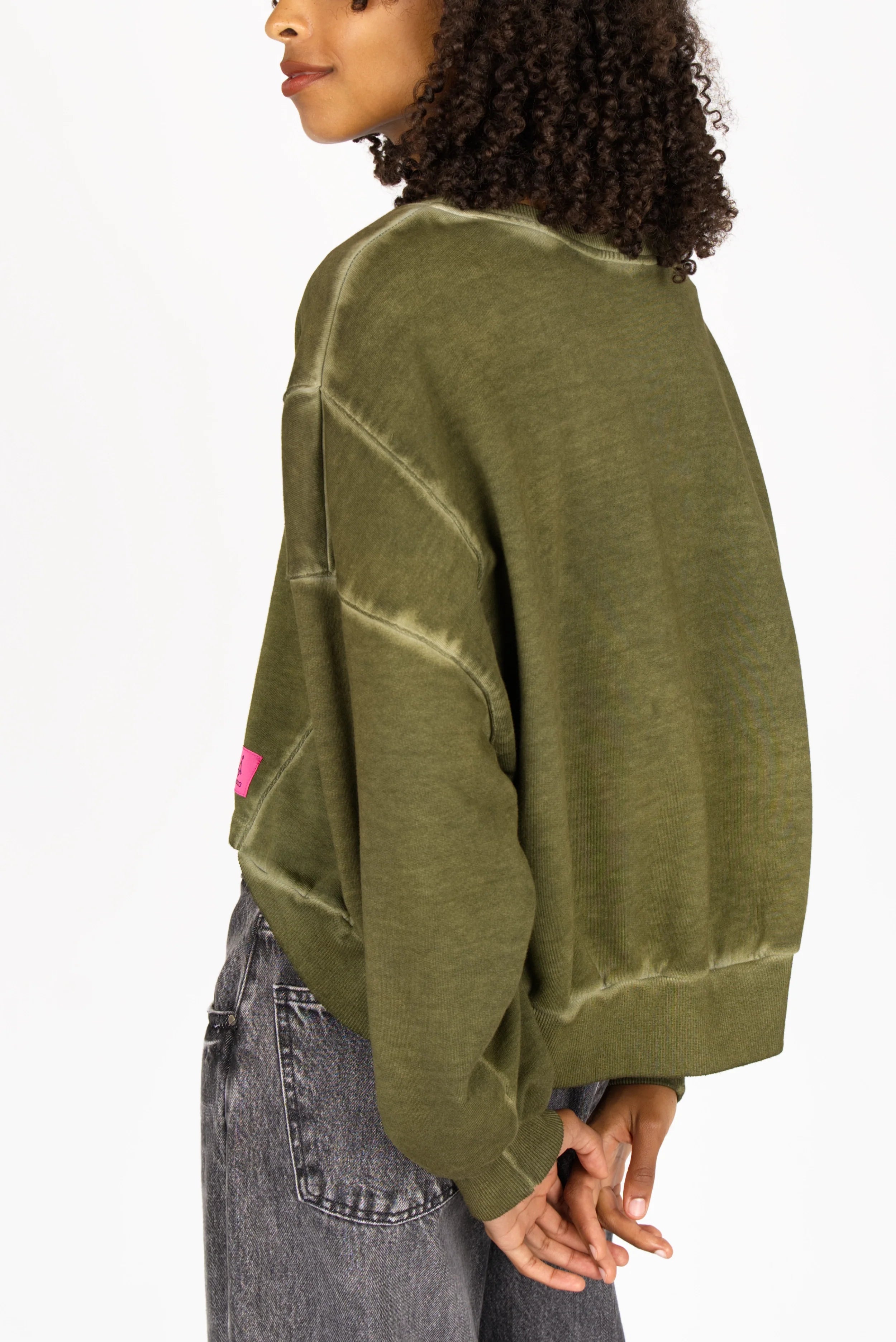 Model wearing olive green KERY Cropped Sweater with oversized fit and U-boat neckline from STUDIO Edition