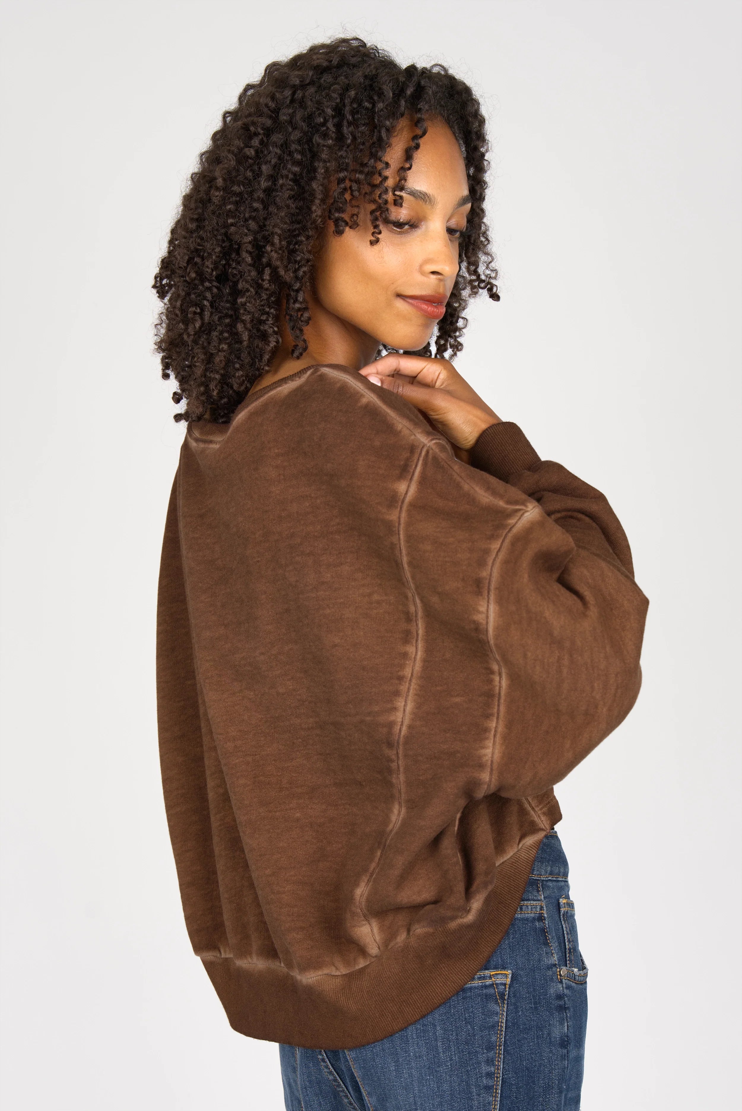 Frau trägt braunen KERY Cropped Sweater mit oversized Passform und U-Boot-Ausschnitt aus cold-washed Baumwolle