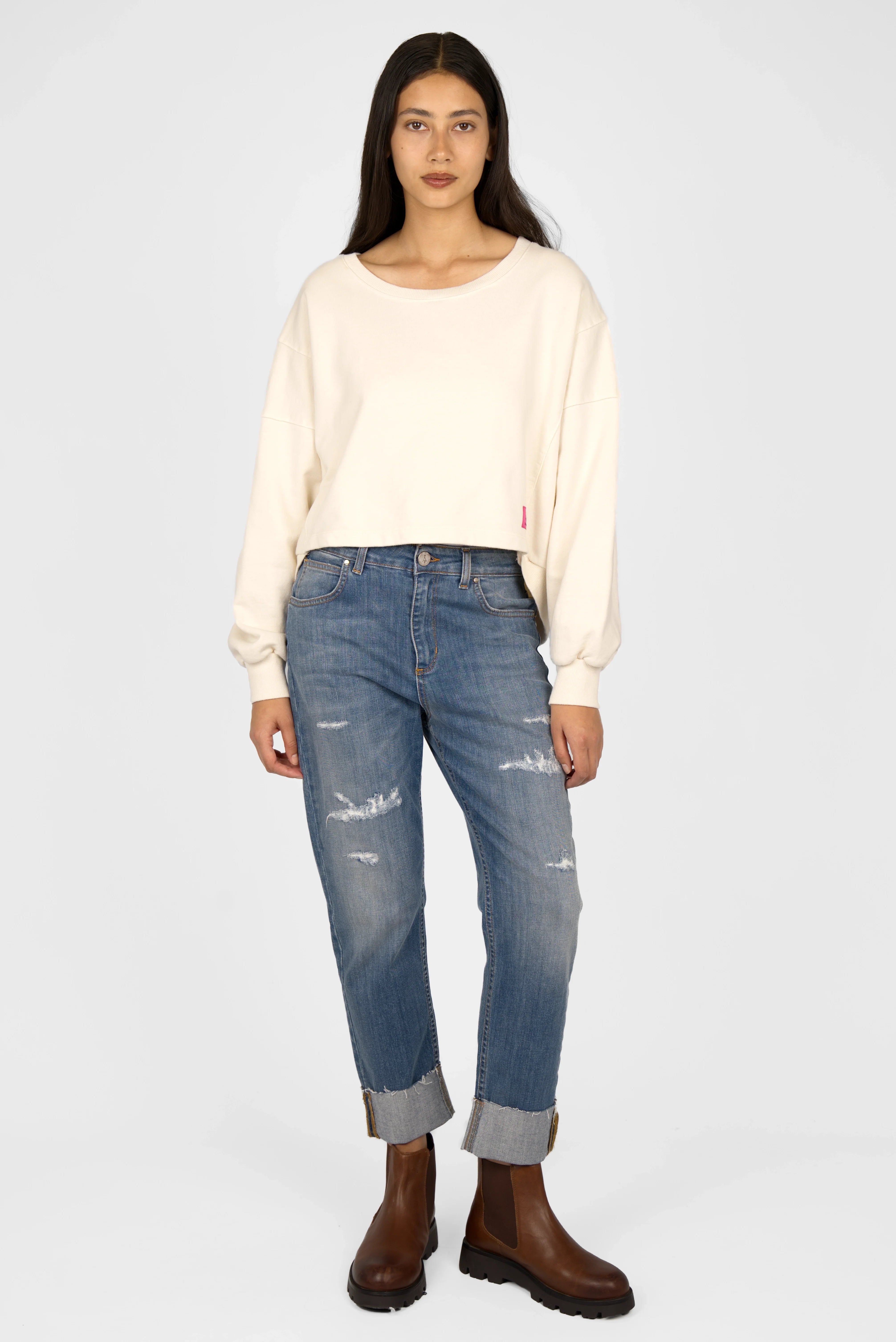 Frau trägt KERY Cropped Sweater in oversized Passform mit U-Boot-Ausschnitt und hinten längerem Saum aus Baumwoll-Sweat in beige