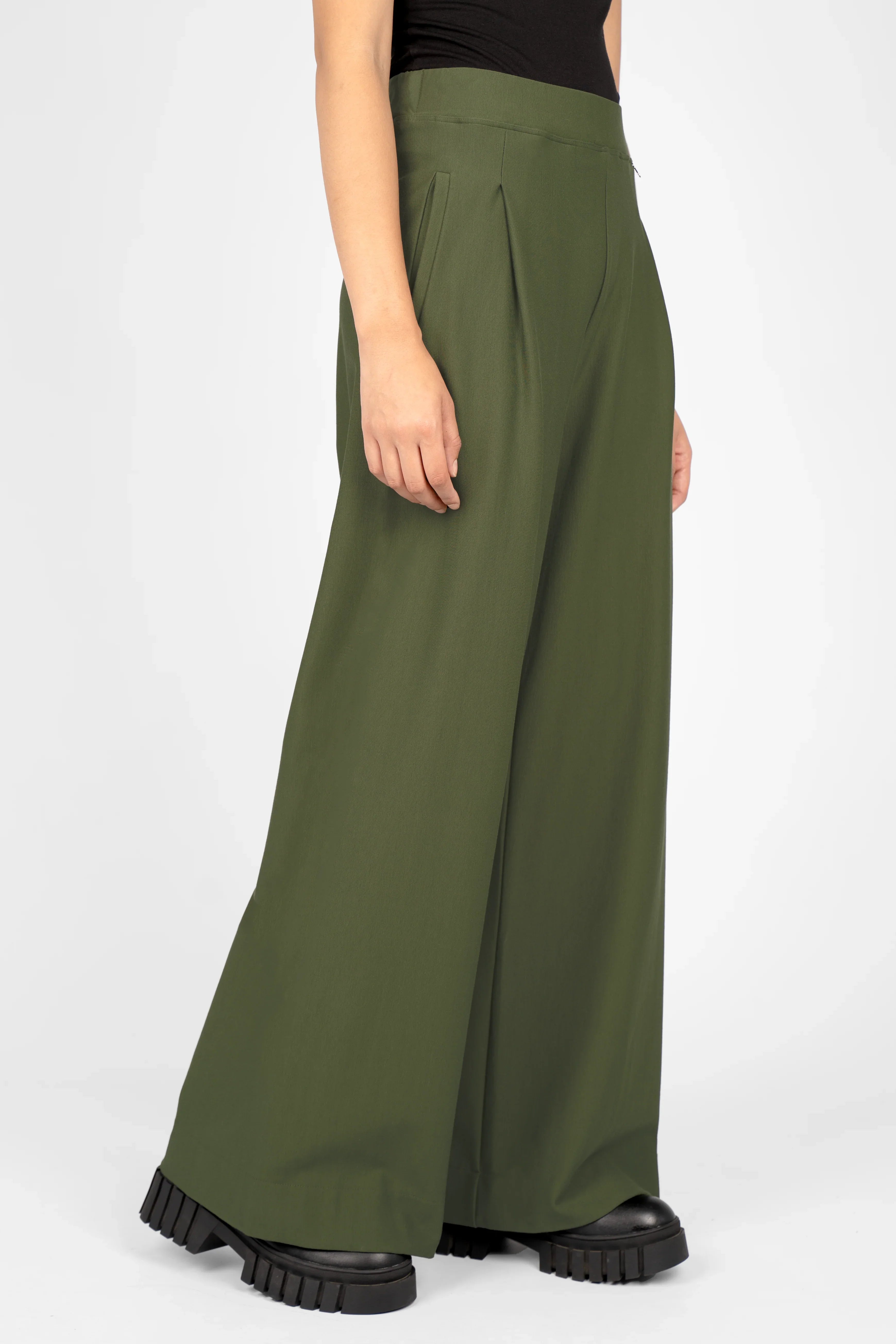 Olive green wide leg pants with elastic waistband and side pockets on model wearing black top and chunky black shoes