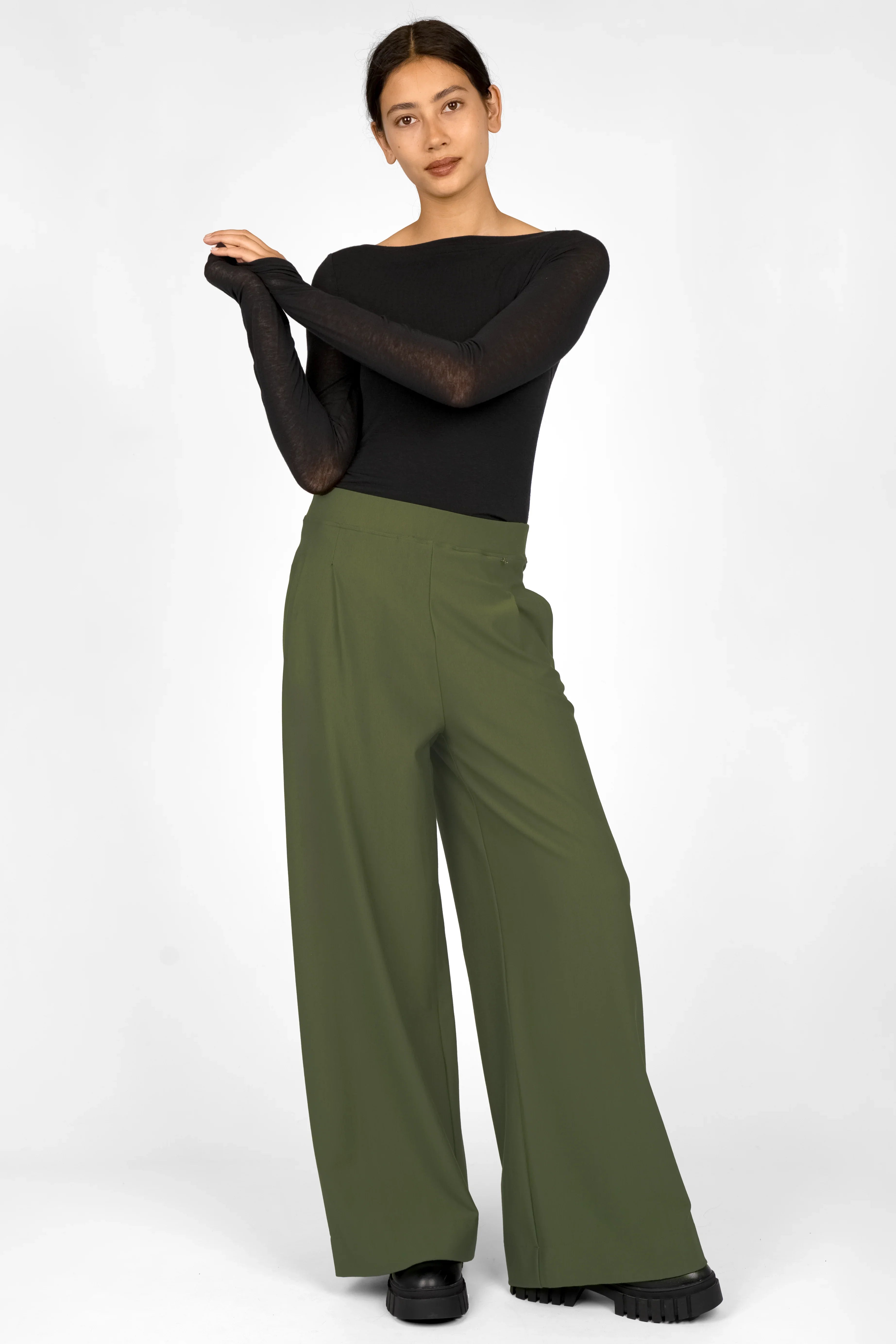 Woman wearing olive green wide leg pants with elastic waistband and side pockets