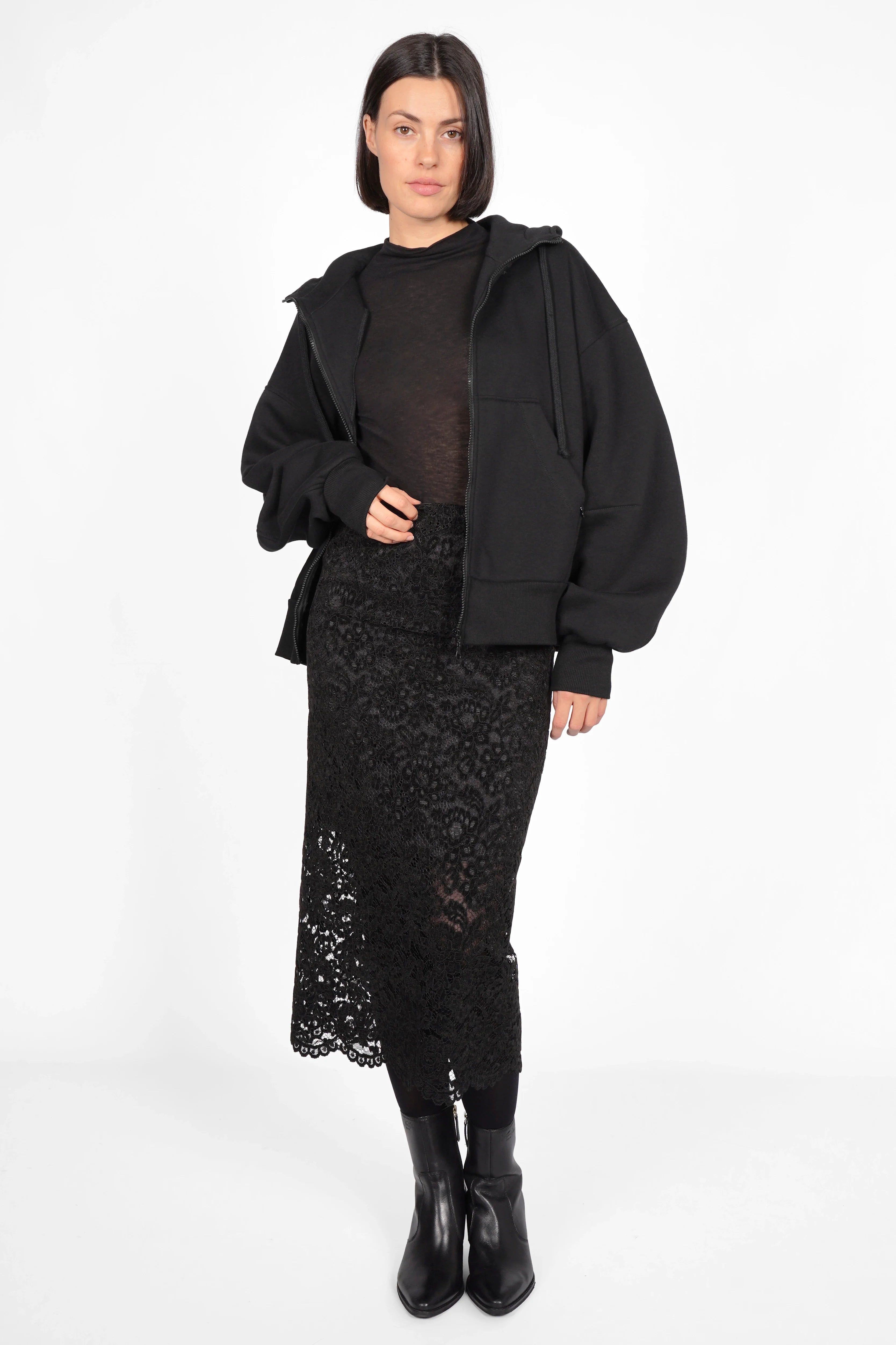 Frau trägt schwarzen LAACE Pencil Rock aus feiner Spitze mit floralem Muster, elastischem Bund und transparentem Saum.