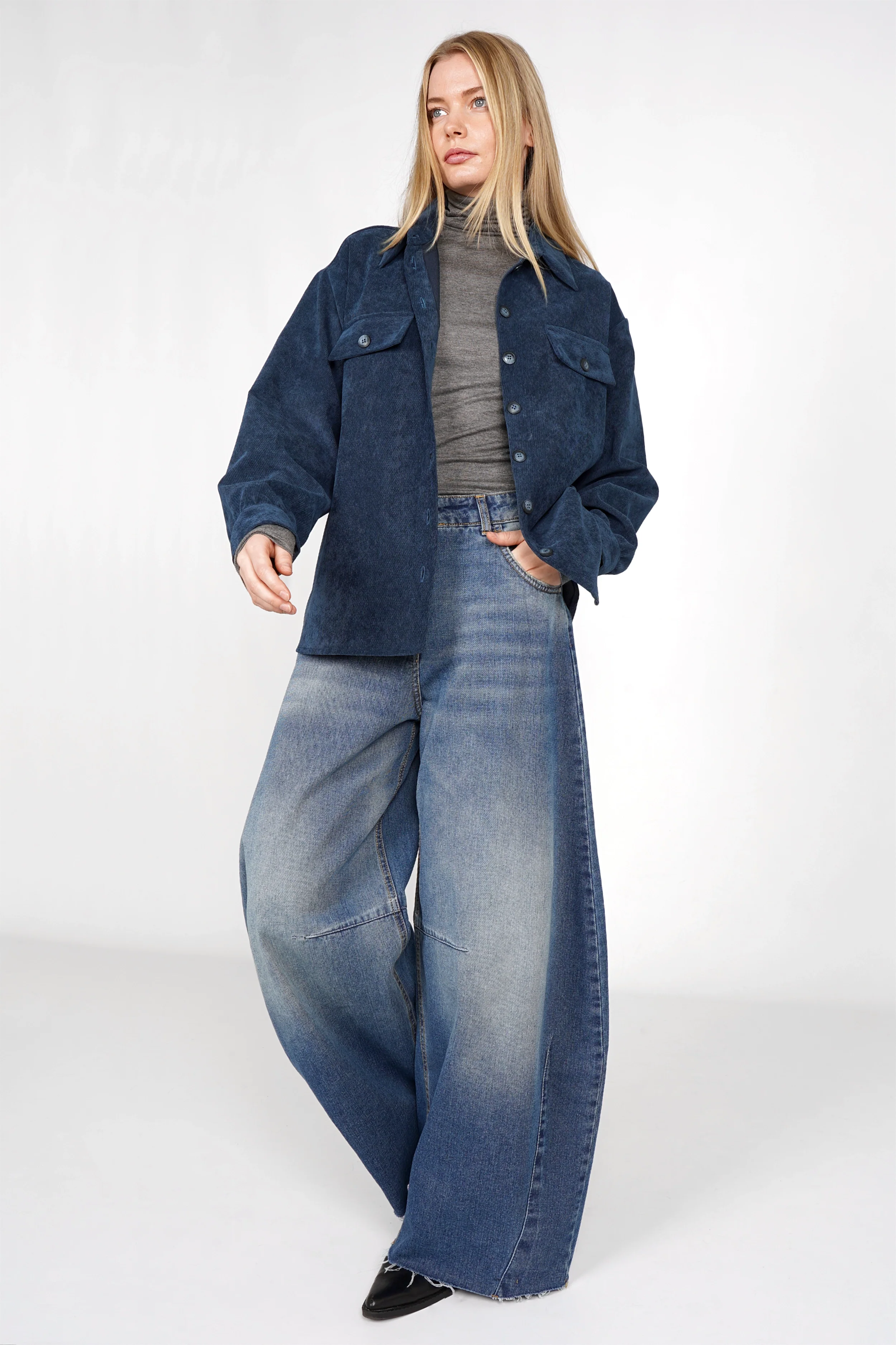 Frau trägt weite Barrel Jeans mit high waist, dezenten destroyed Details, Raw-Cut Saum und lässiger Silhouette