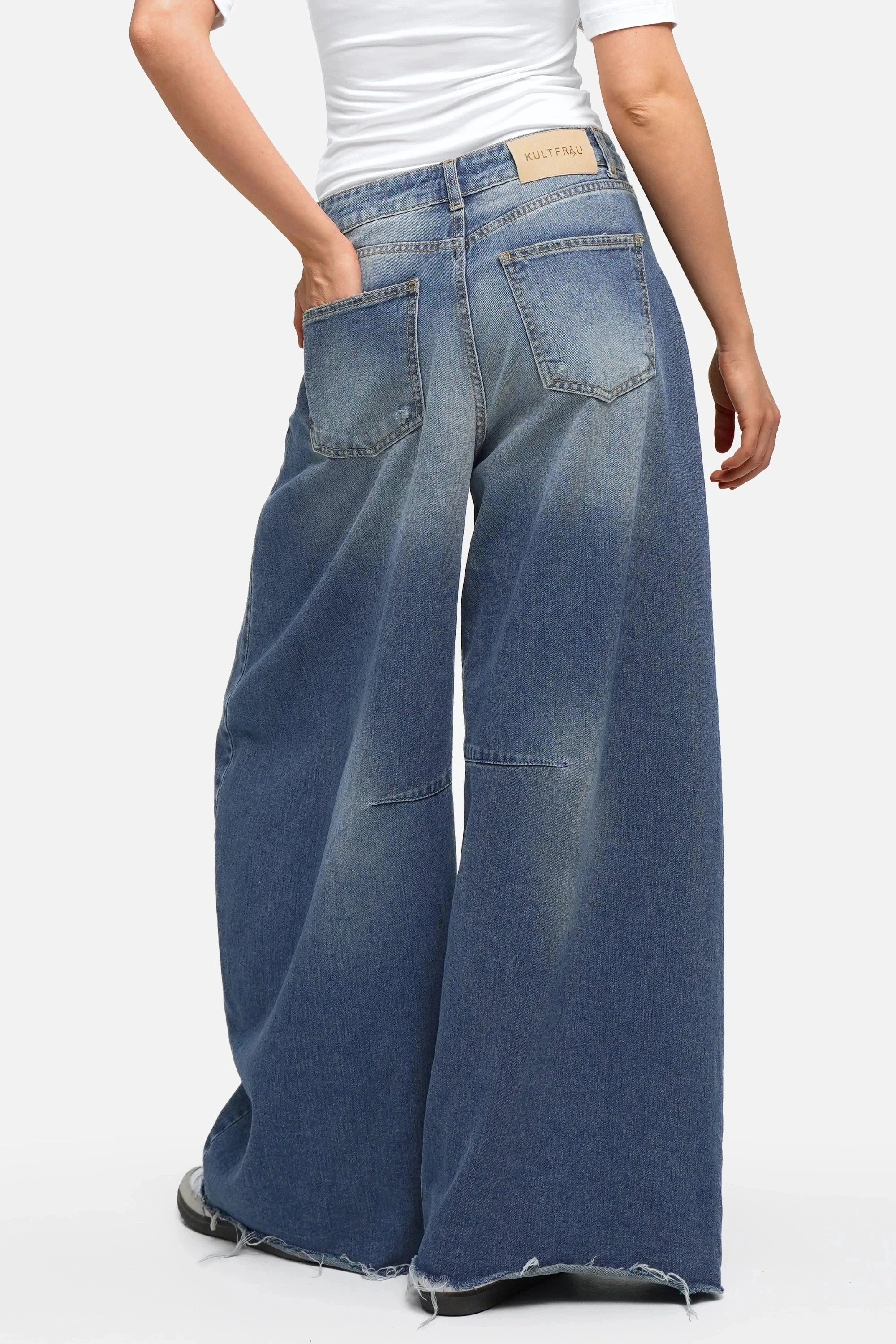 Damen tragen weite Barrel Jeans aus Mid Blue Baumwoll-Denim mit Raw-Cut Saum und 5 Pocket Design