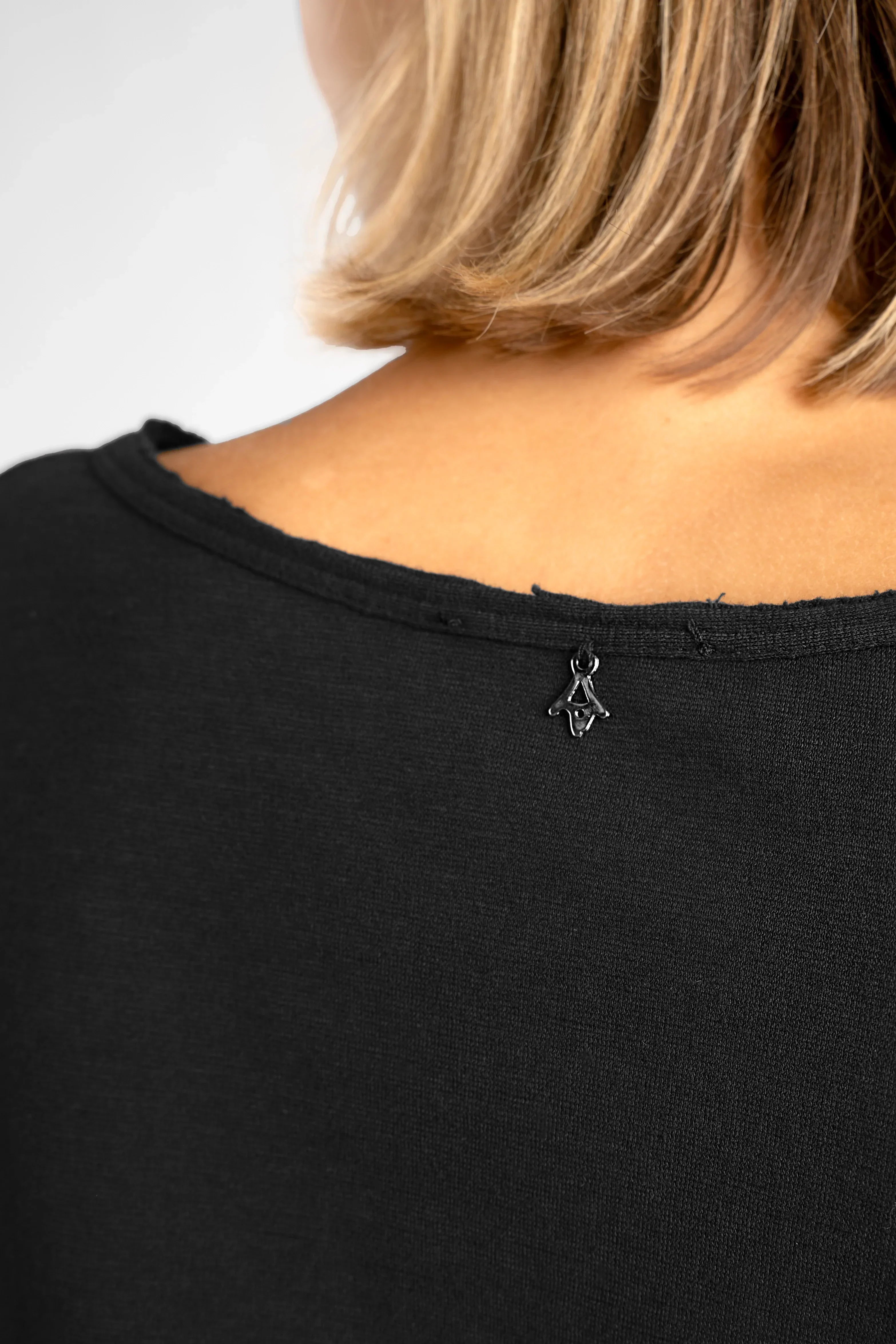 Close-up of black LARXA Longsleeve showing round neckline with raw edges and slub-jersey fabric texture