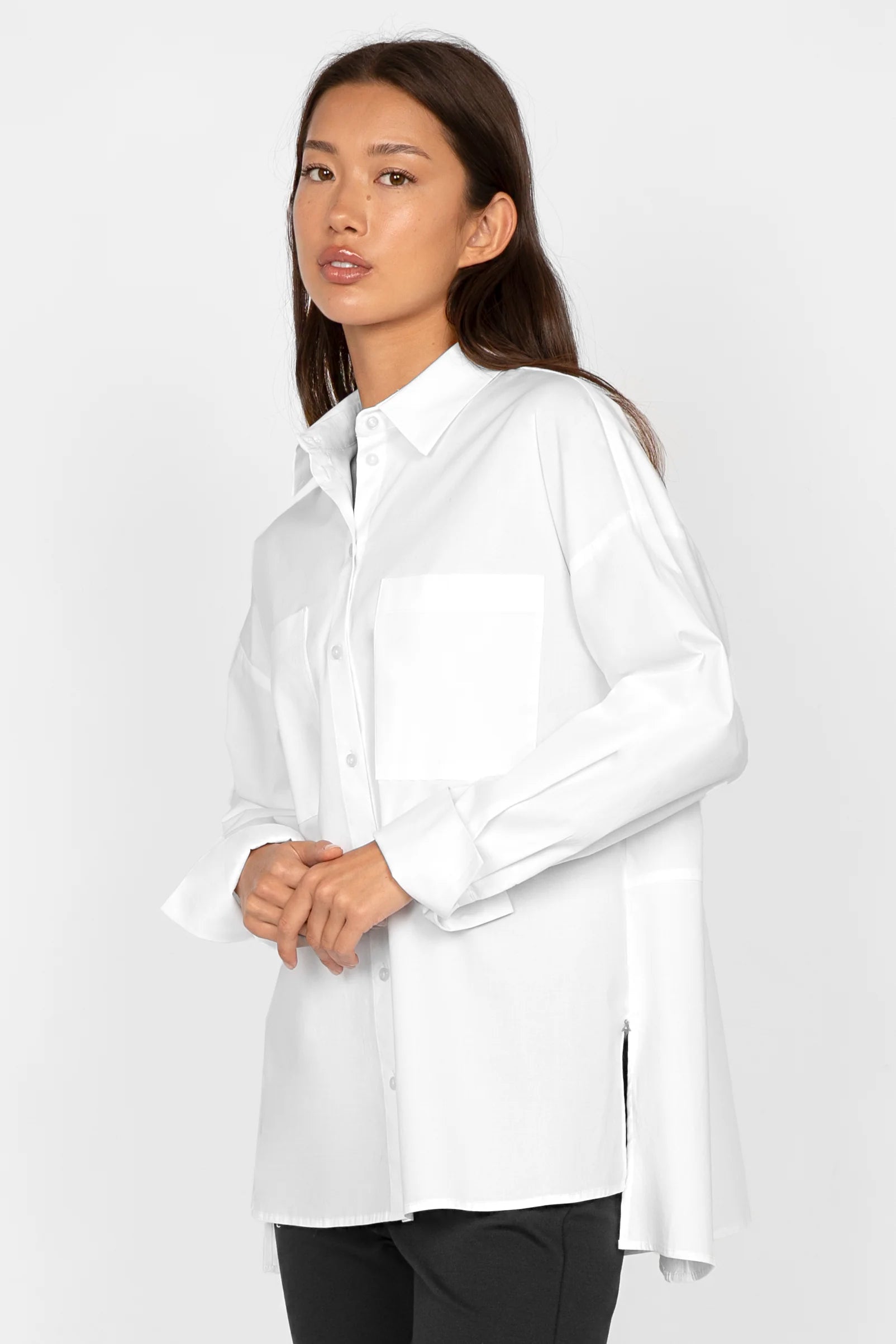 Woman wearing white LEA.K Loose Fit cotton poplin blouse with chest pockets and long sleeves