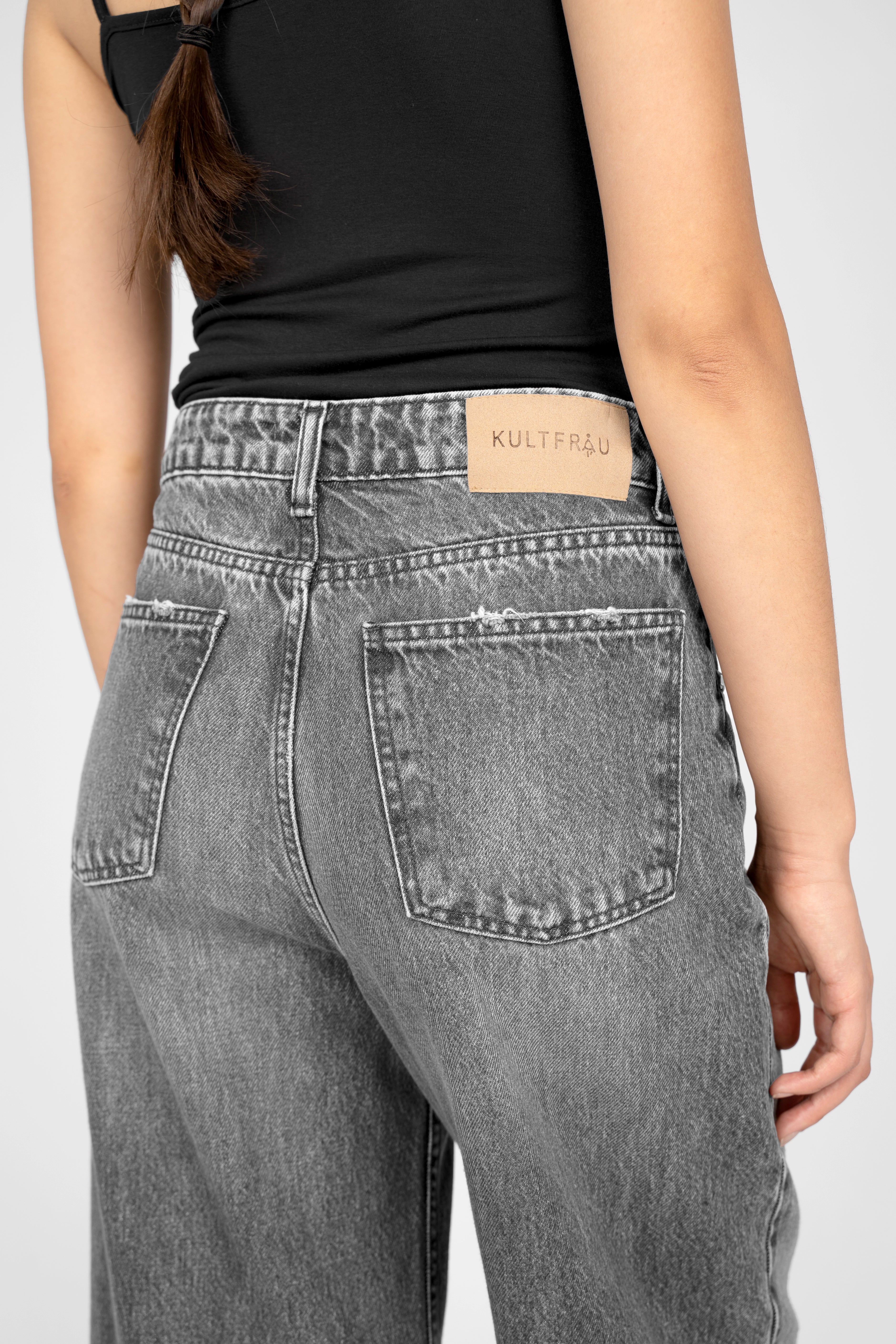Back view of LIAME Cropped Jeans with raw-cut cuff and whisker effect in gray denim on a model wearing a black top