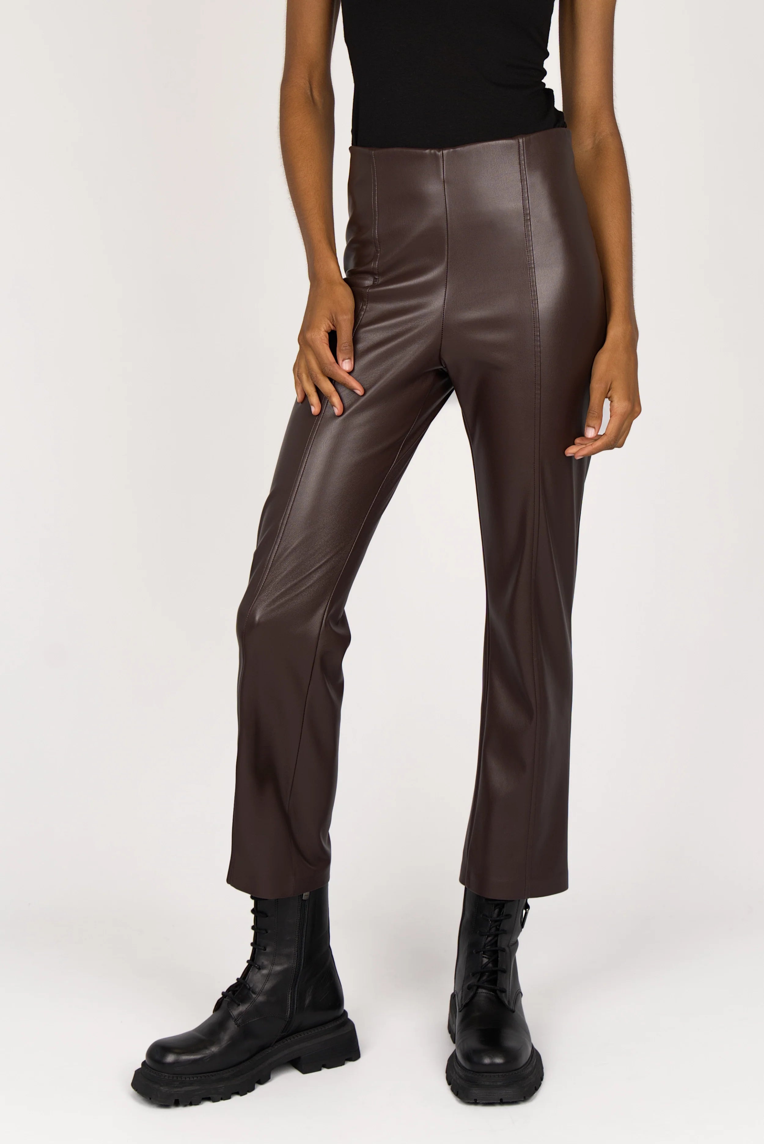 Woman wearing LIMGARD flared eco-leather pants with cropped length and high waist elastic band