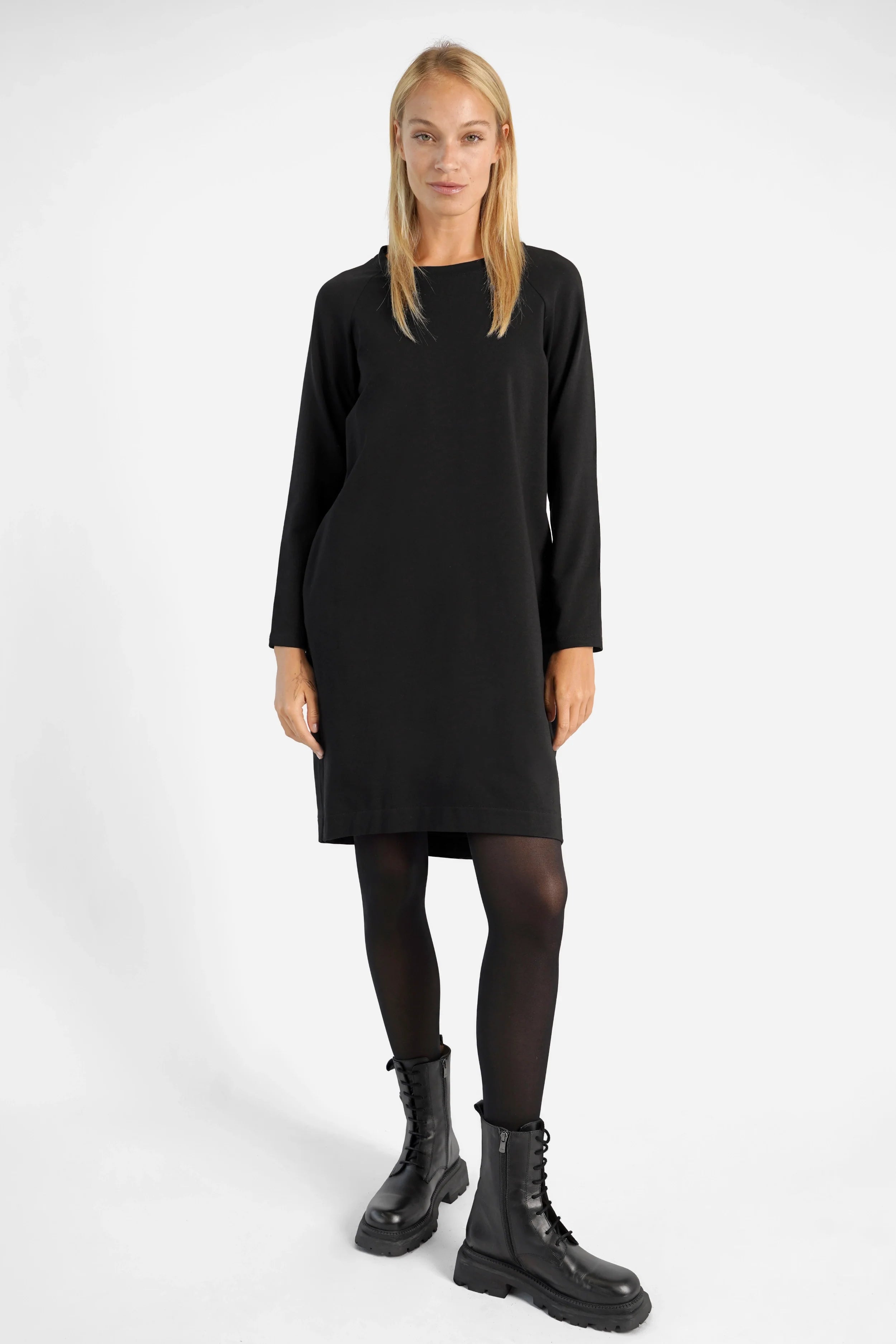 Woman wearing black LIZ Sweatkleid with long sleeves and round neckline, styled with black tights and boots.