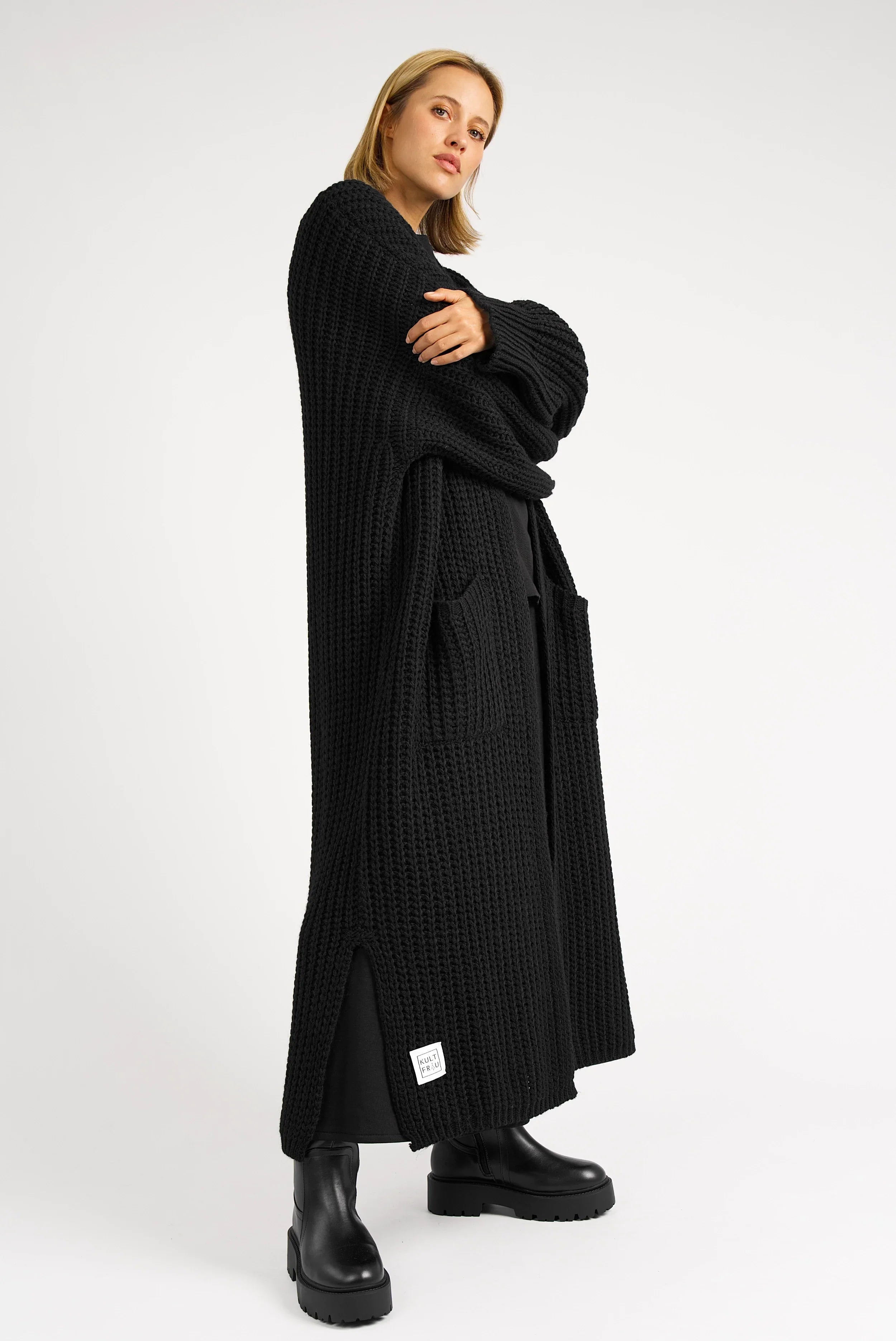 Frau trägt schwarzen LOLA Strickcardigan mit Oversize-Schnitt und aufgesetzten Taschen