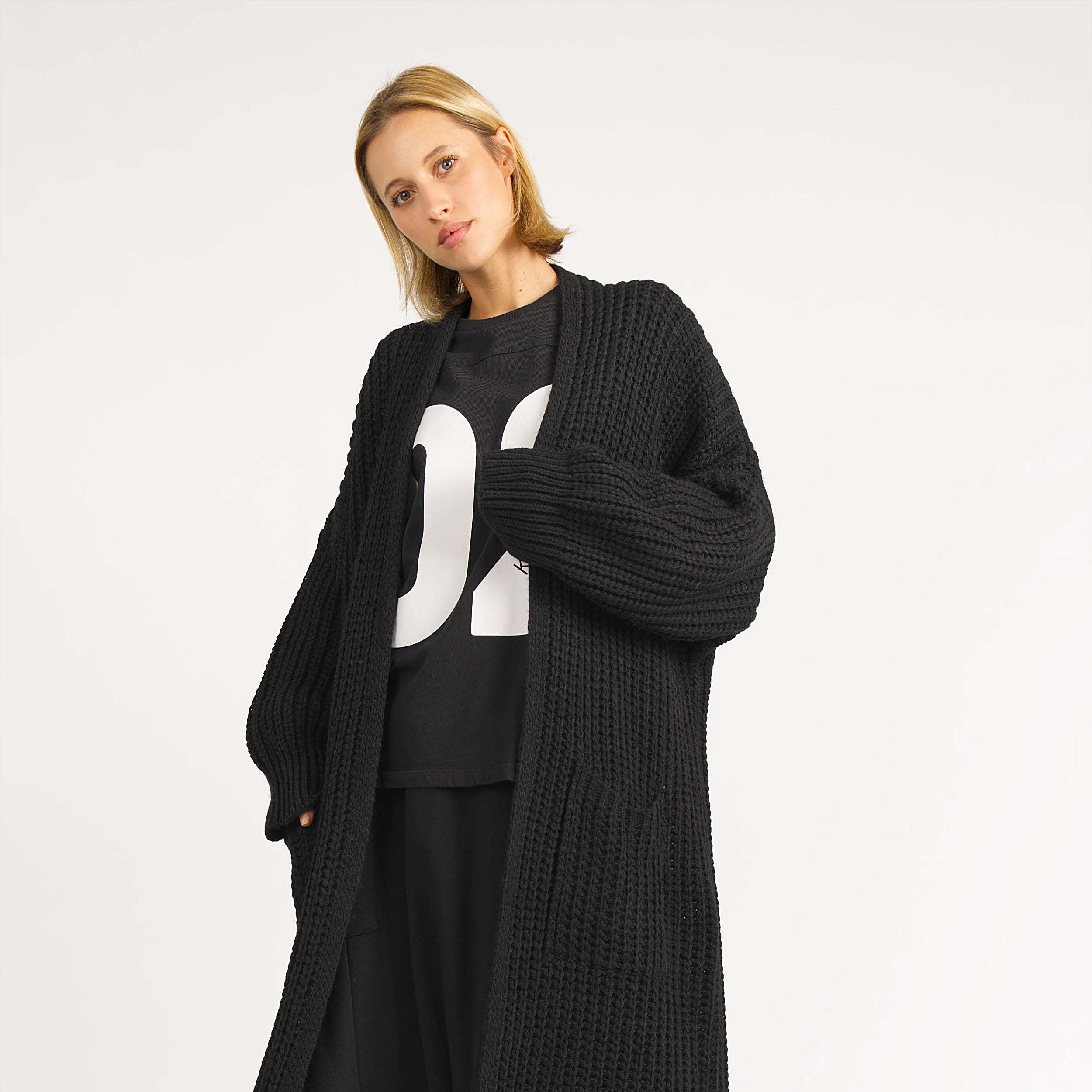 Damen trägt langen schwarzen LOLA Strickcardigan oversized mit aufgesetzten Taschen und lockerem Schnitt