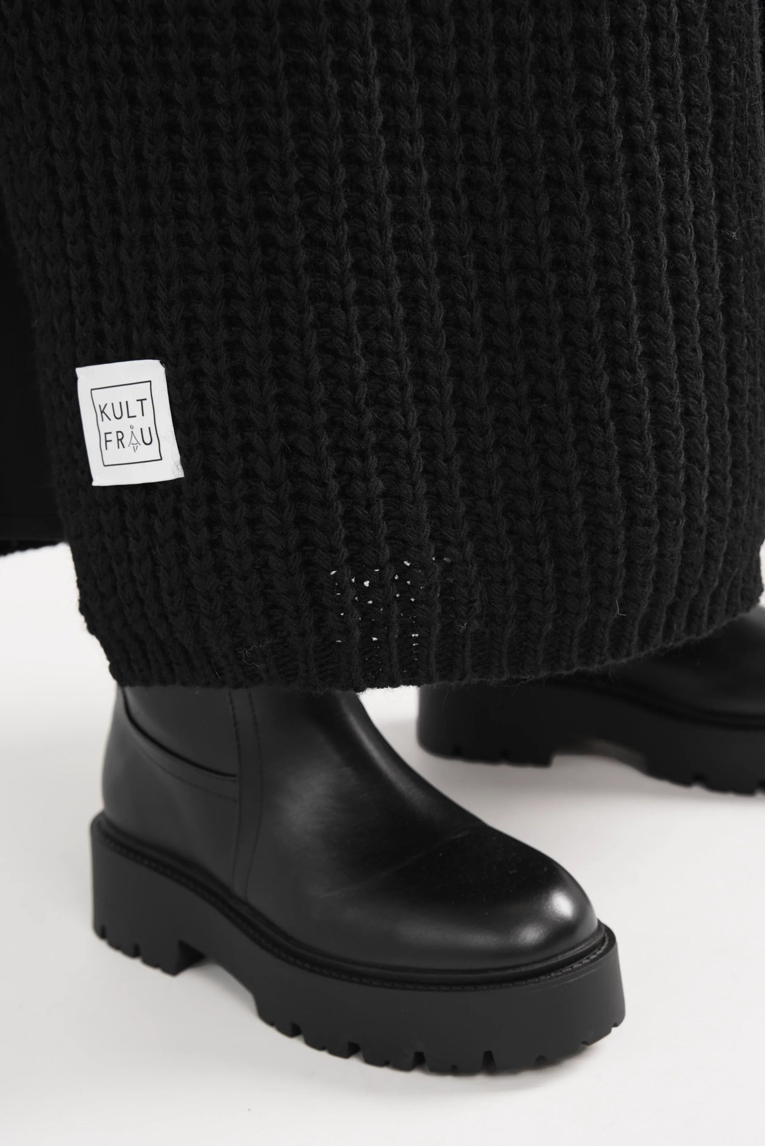 Close-up of black LOLA Strickcardigan knit fabric with Kultfrau label and black chunky boot