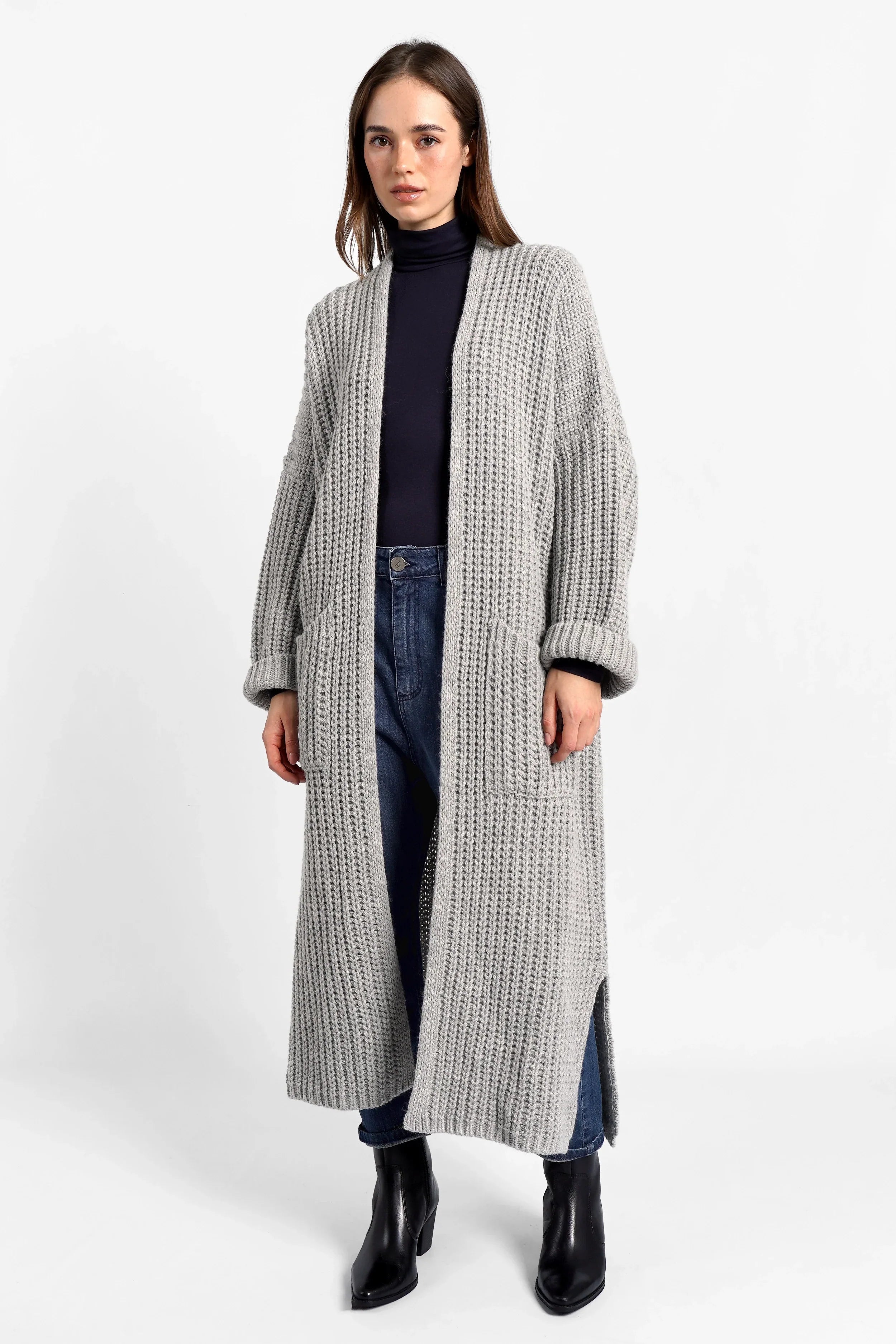 Frau trägt grauen LOLA Strickcardigan, offen, oversized, mit umgeschlagenen Ärmeln und aufgesetzten Taschen