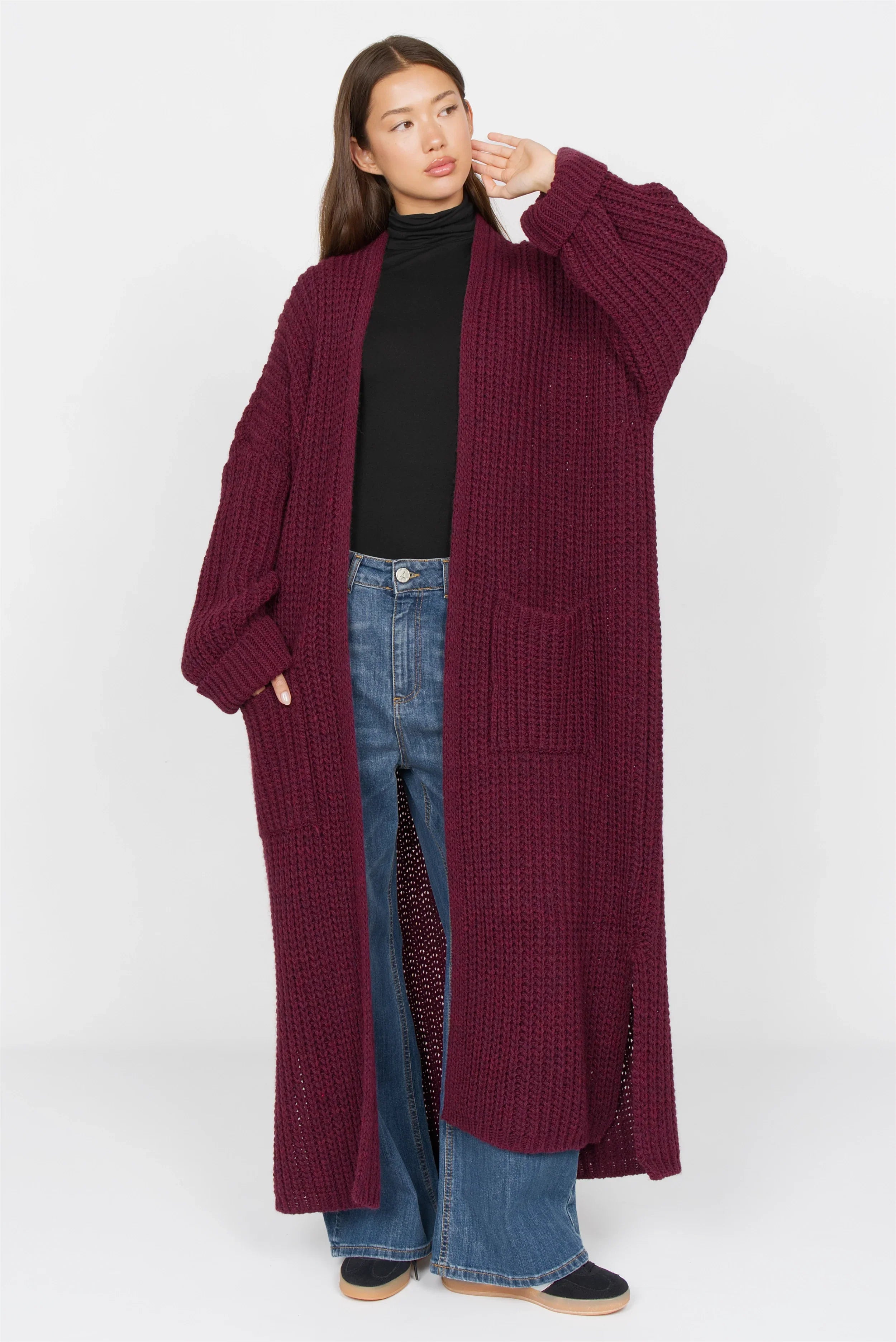 Frau trägt LOLA Strickcardigan in Oversize, offen, weinrot, mit aufgesetzten Taschen und lockerem Schnitt