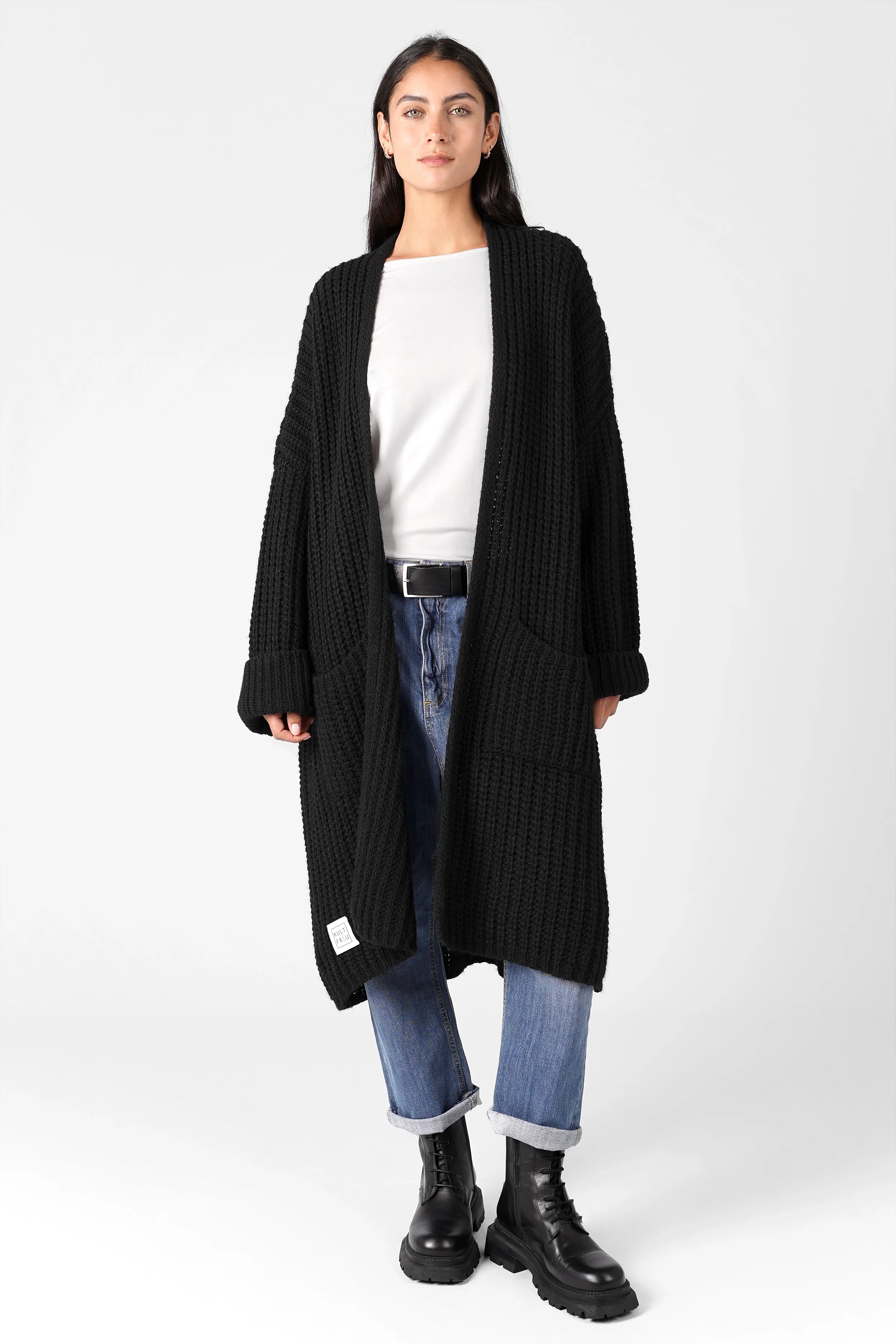 Frau trägt schwarzen LOLLYTA Strickcardigan oversized offen mit umgeschlagenen Ärmeln zu weißem Shirt und blauen Jeans