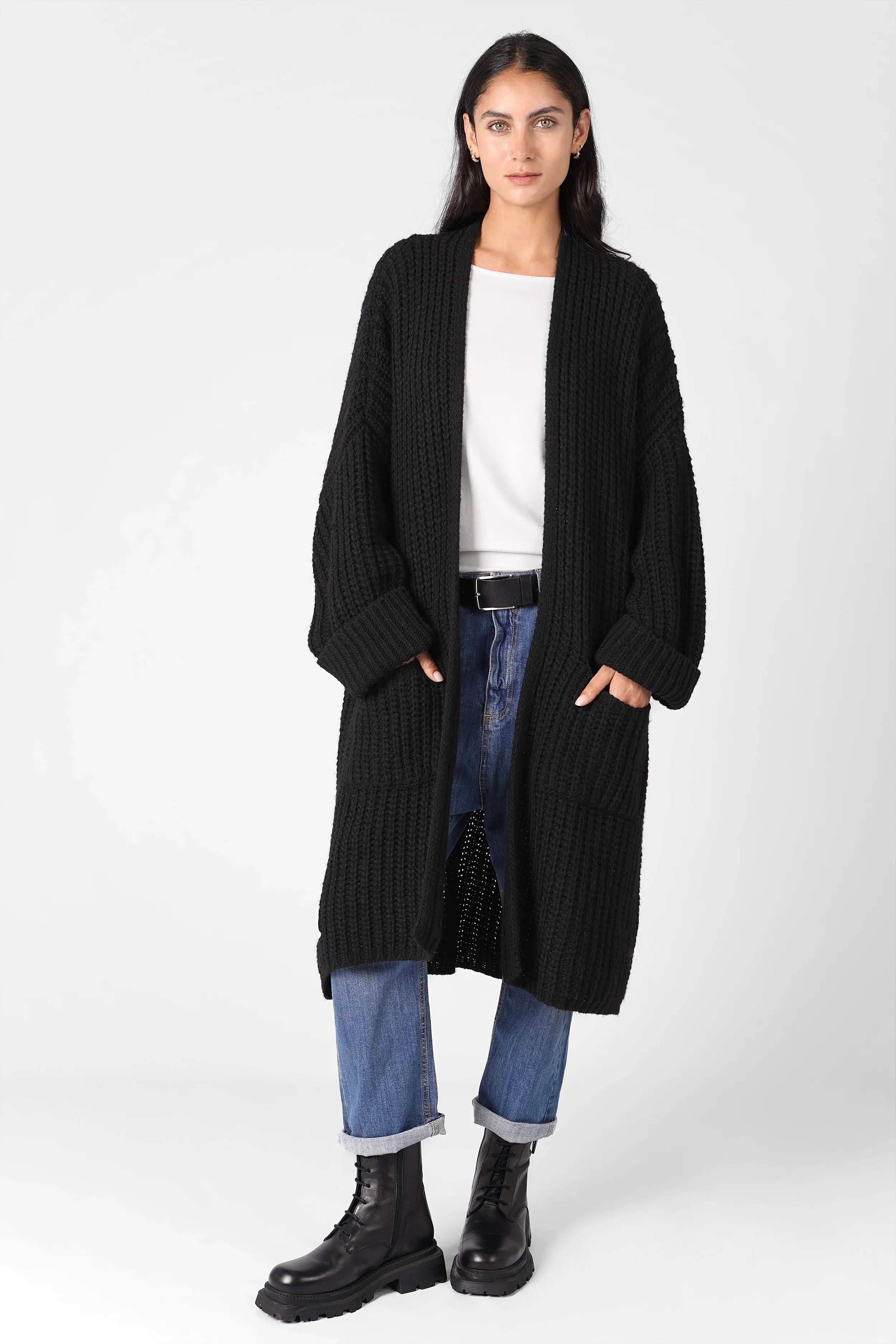 Frau trägt schwarzen oversized Strickcardigan offen mit aufgesetzten Taschen und umgeschlagenen Ärmeln