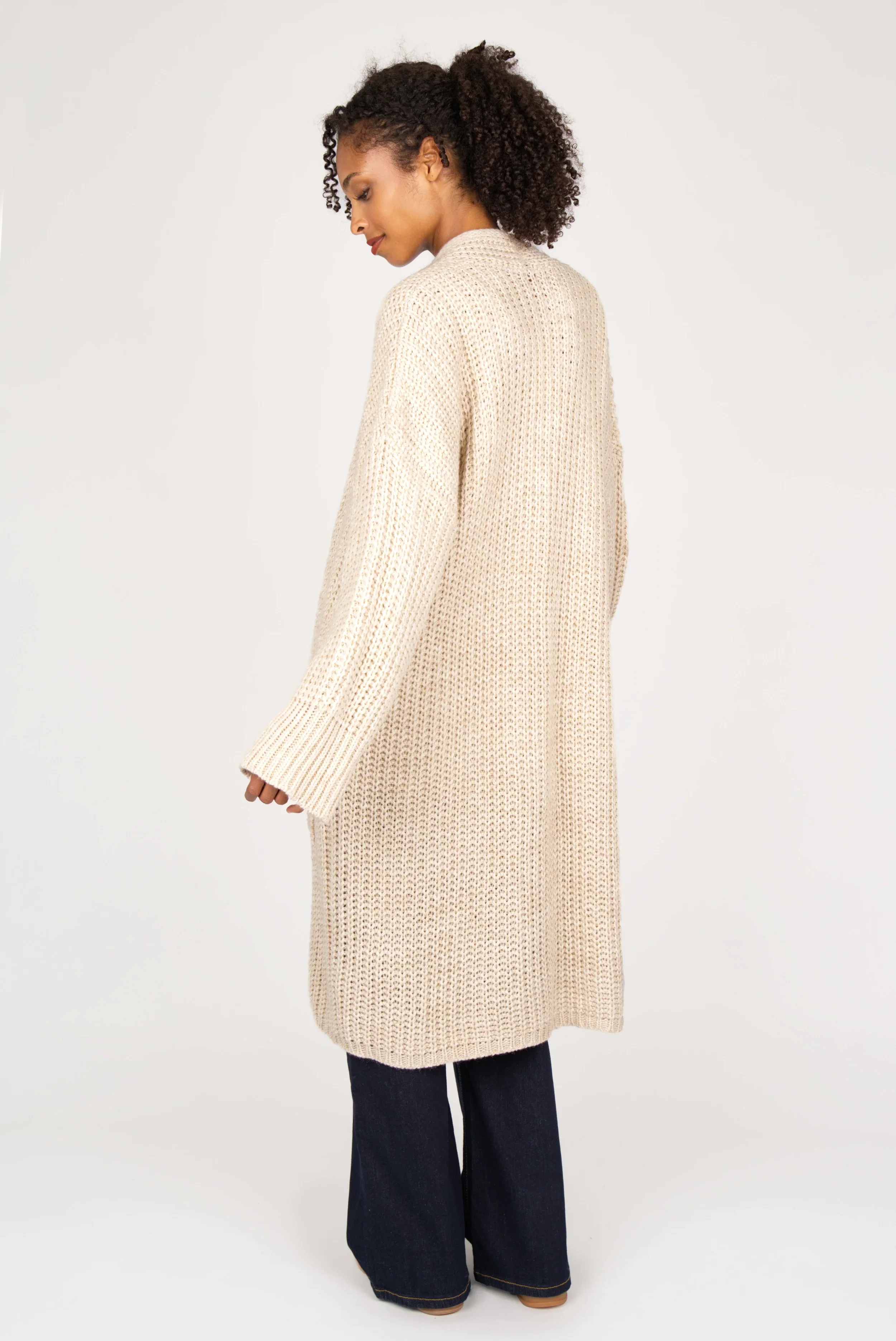 Woman wearing oversized beige LOLYTA Strickcardigan with relaxed fit and dropped shoulders, styled open over dark pants.