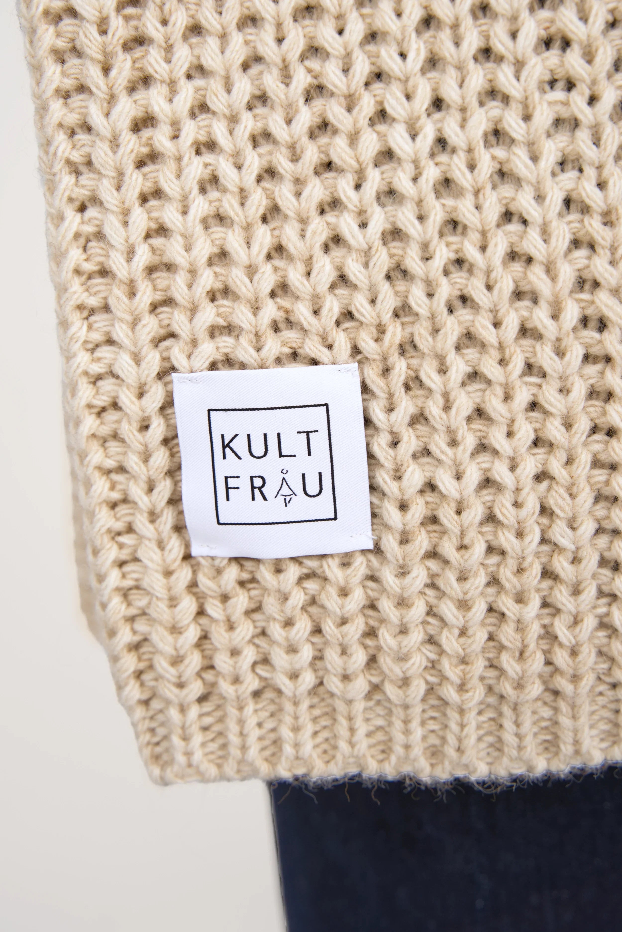 Close-up of beige LOLYTA Strickcardigan knit fabric with Kultfrau brand label.