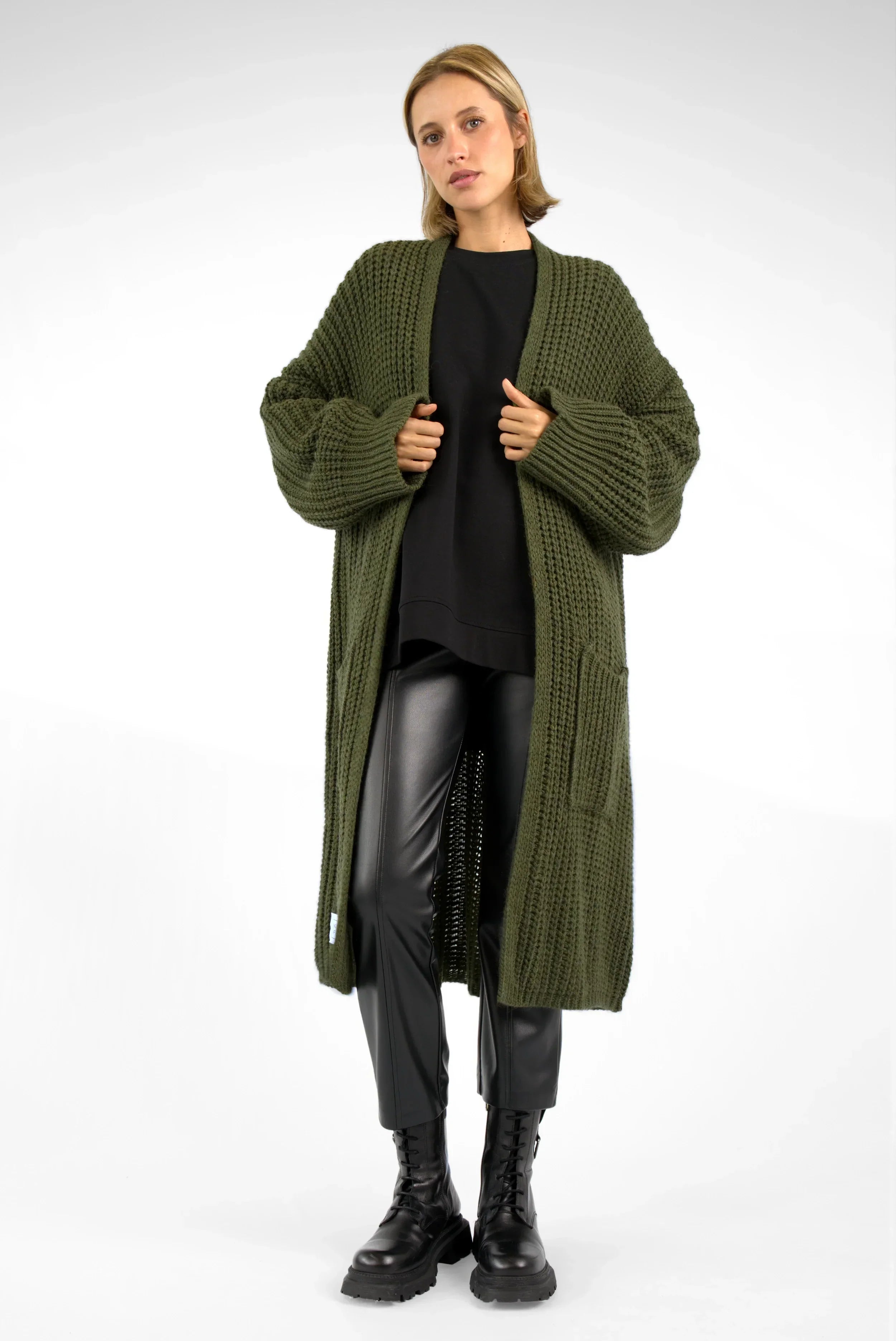 Frau trägt oversized grünen LOLLYTA Strickcardigan mit aufgesetzten Taschen und überschnittenen Schultern, offen getragen.