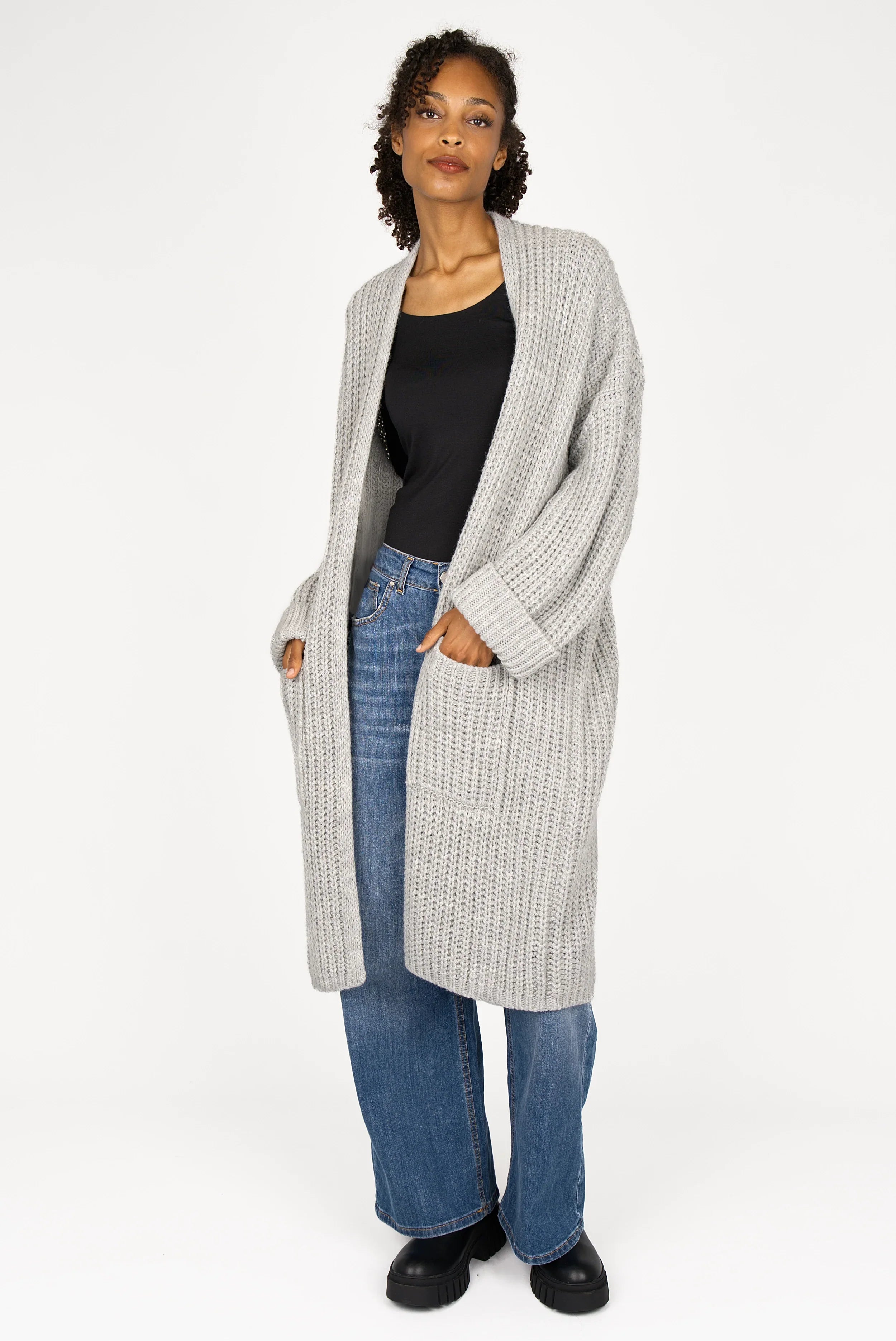 Frau trägt LOL Strickcardigan oversized offen mit aufgesetzten Taschen und überschnittenen Schultern in Hellgrau
